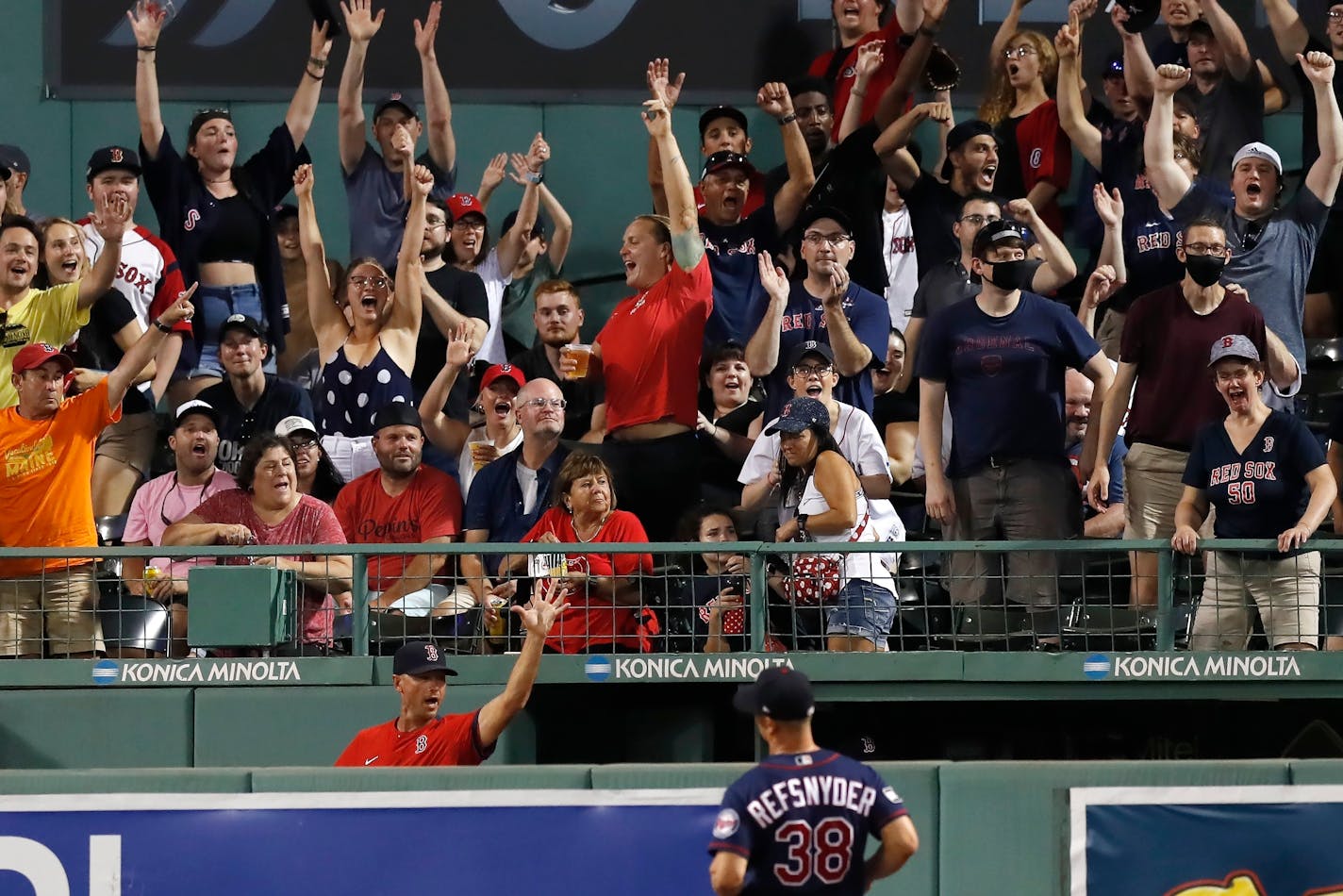 Fans reacts to the two-run home run by Boston Red Sox's Rafael Devers in front of Minnesota Twins' Rob Refsnyder (38) during the sixth inning of a baseball game, Thursday, Aug. 26, 2021, in Boston. (AP Photo/Michael Dwyer)