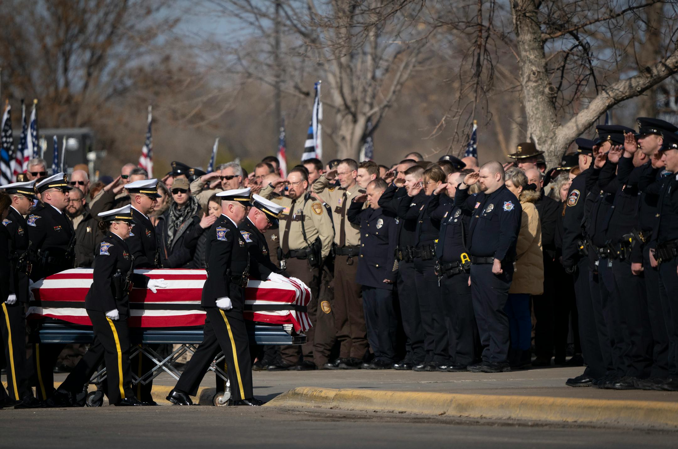 Honor guard palbearers escort Pope County deputy Josh Owen's casket into the building for the visitation and funeral of as hundreds of officers stand at attention at the entrance.