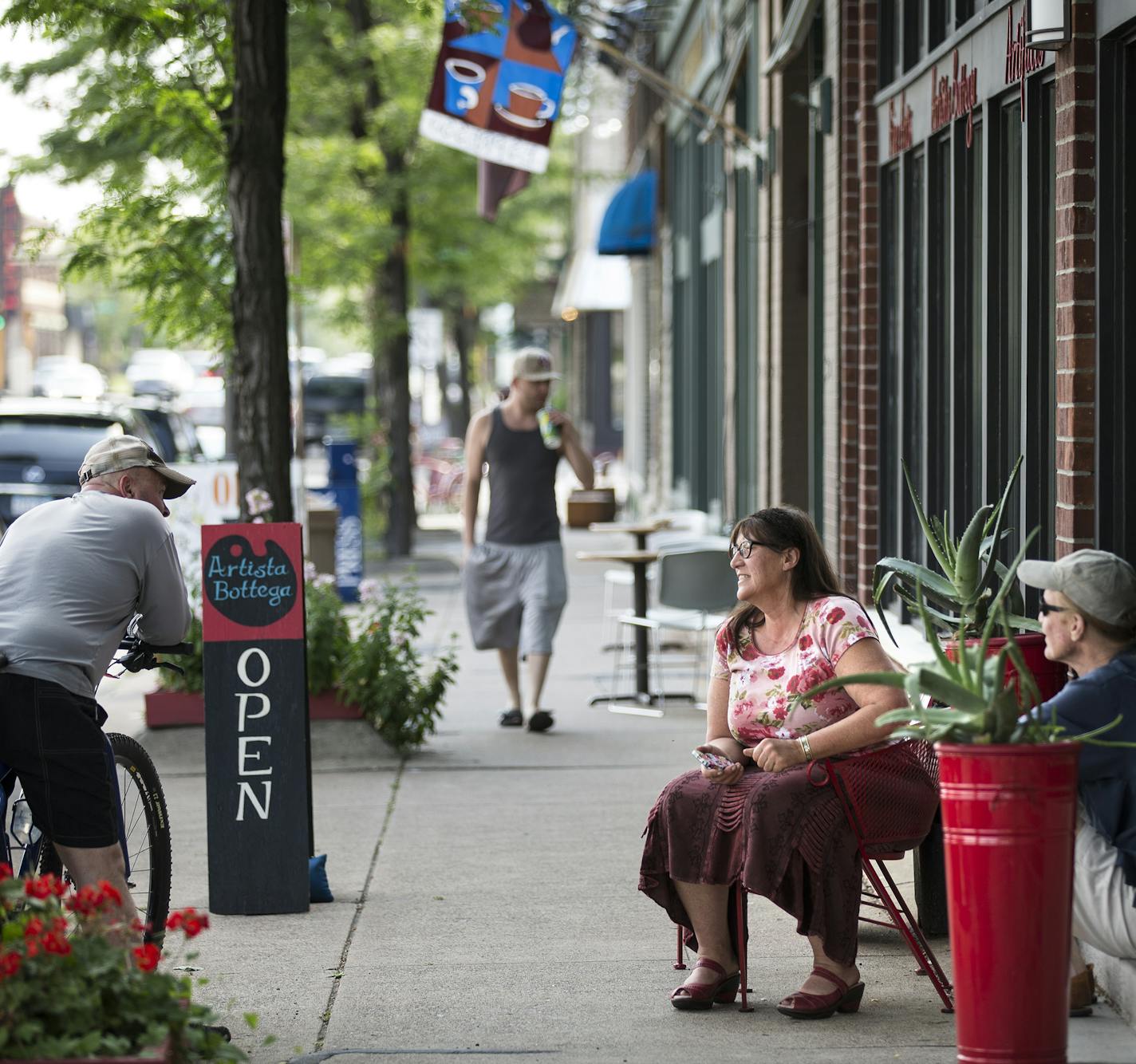 John Davidson, from right, and Nance Derby Davidson, owners of Artista Bottega, sits outside their storefront chatting with neighbor Scott Stevenson, on bike, who moved to the neighborhood one month ago, on 7th Street West in St. Paul on Thursday, July 9, 2015. ] LEILA NAVIDI leila.navidi@startribune.com /