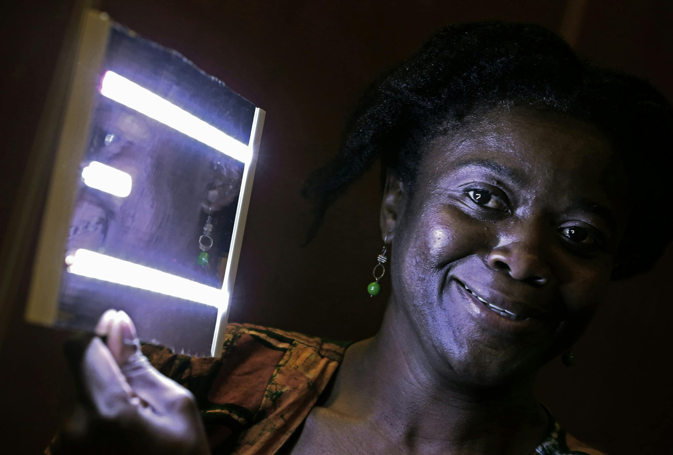 A day to celebrate: 3M employees, top, looked at the Tesla S electric car as part of the 3M celebration of Earth Day, which featured displays of other sustainable 3M products. Above, 3M employee Oredola Taylor held one of the LED lights assembled by 3M employees as part of the 3Mgives-Team Africa and New Vision program, while software engineer Elisa Collins got into the cockpit of the 2014 Tesla Model S sedan.