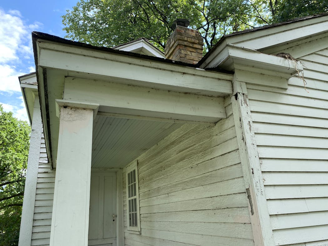 Peeling paint, animal holes and a bird nest are visible at one corner of the Stevens House.