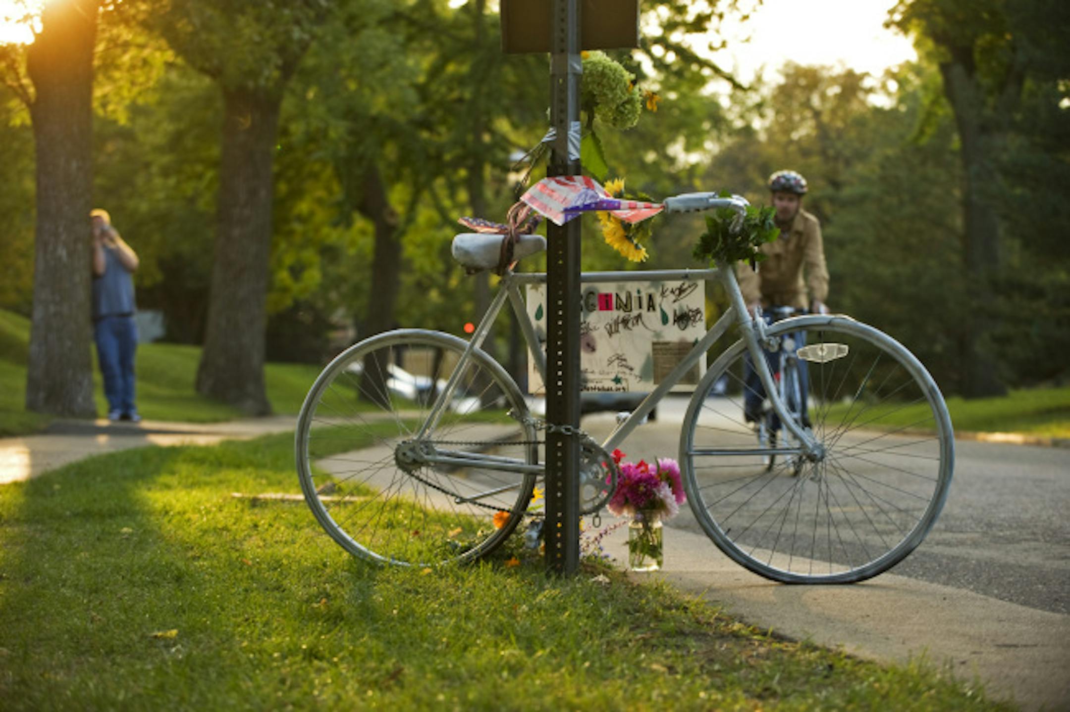 Passers by view the "ghost bike" at the scene of the accident on Summit Av. east of Snelling where Virginia Heuer-Bower lost her life Saturday morning. Ghost bikes are painted white and left near the scene of an accident to commerate a cyclist who has lost their life in a traffic accident.
