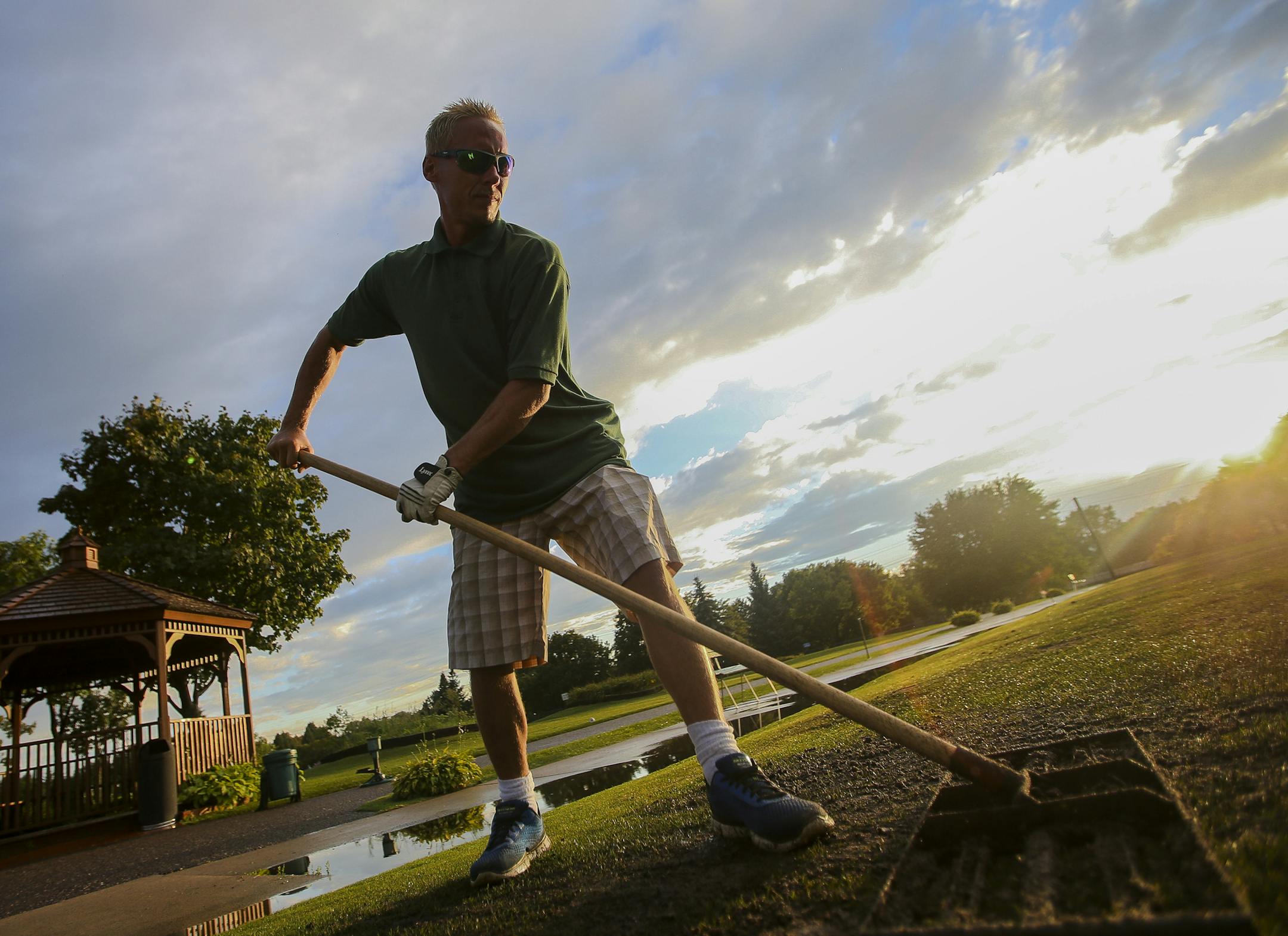 Golf course porter Joshua Ulmsted resurfaces driving range tee boxes as the sky opens up following a rainstorm. ] Timothy Nwachukwu • timothy.nwachukwu@startribune.com A large band of rainstorms hindered couples from attending a date night of chip-n-putt golf at Parkers Lake Golf Center on Friday, August 12, 2016 in Plymouth. However, the rains were not enough to keep golf course porters from tending to the state-of-the-art golf course.