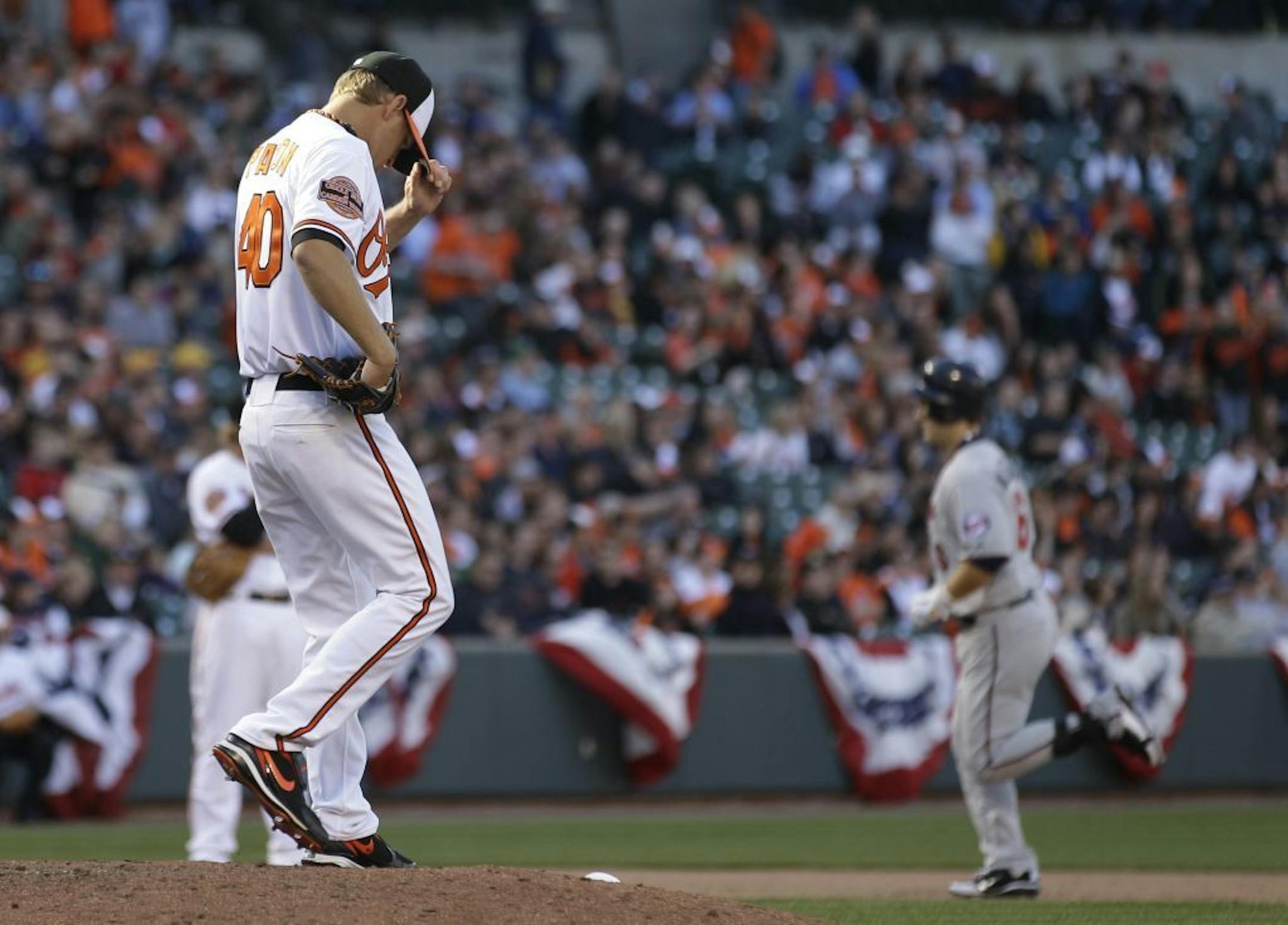 Baltimore Orioles relief pitcher Troy Patton, left, walks on the mound as Minnesota Twins' Josh Willingham rounds the bases after hitting a two-run home run in the ninth inning of the Orioles' home opener baseball game in Baltimore, Friday, April 6, 2012. Baltimore won 4-2.