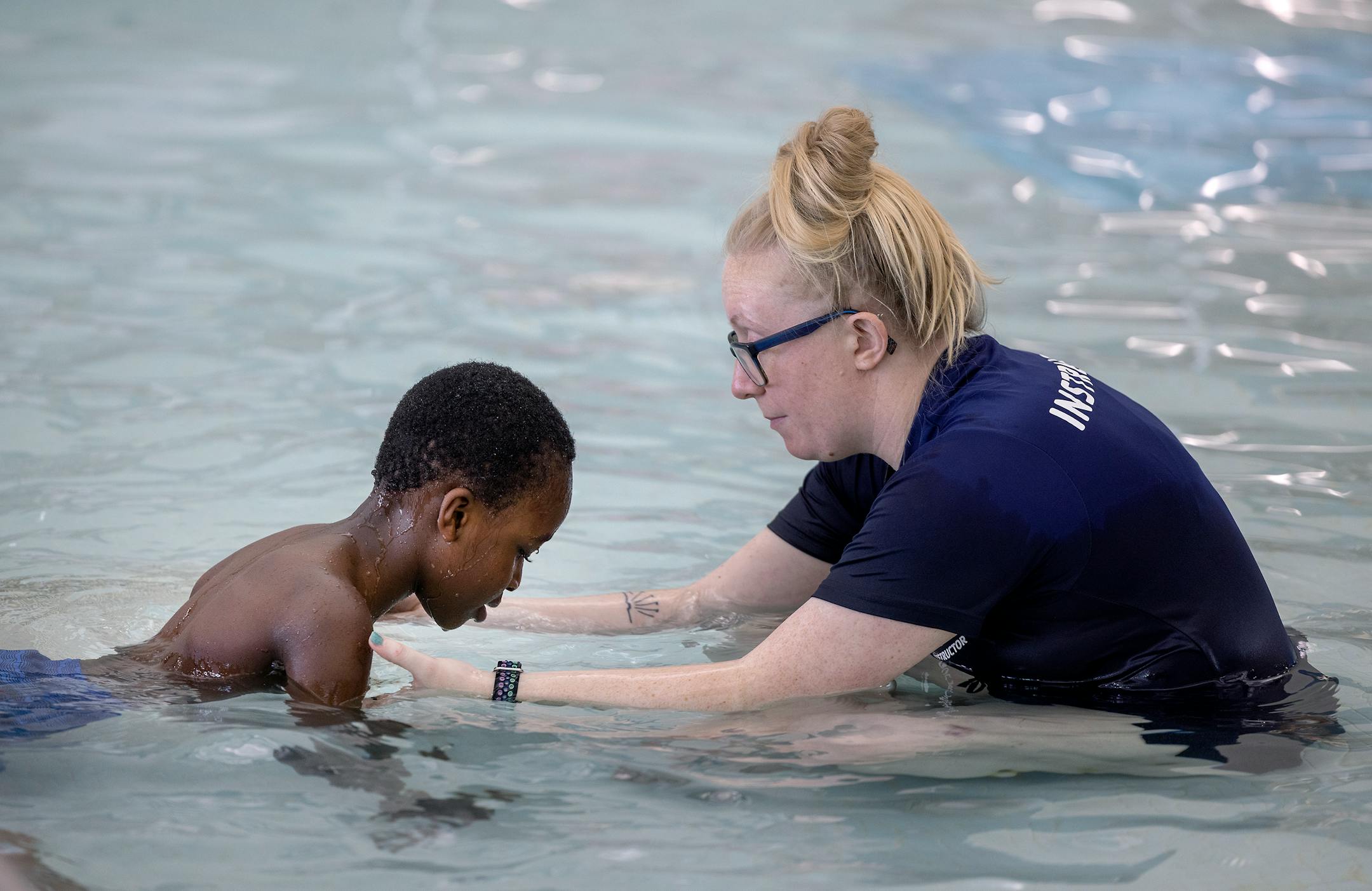 Kaitlin Pohland, the aquatics director for the St. Cloud YMCA, guides a Madison Elementary second-grader in the pool.