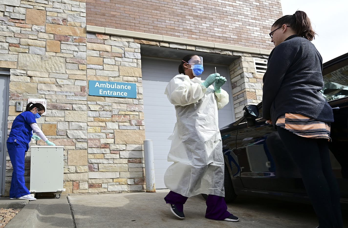 Medical assistants Sandy Graves, left, and Reece Wallaker demonstrated with the help of fellow M Health Fairview employee Nichole Brown, right, how to administer a COVID-19 test outside the system's Fridley clinic Tuesday.