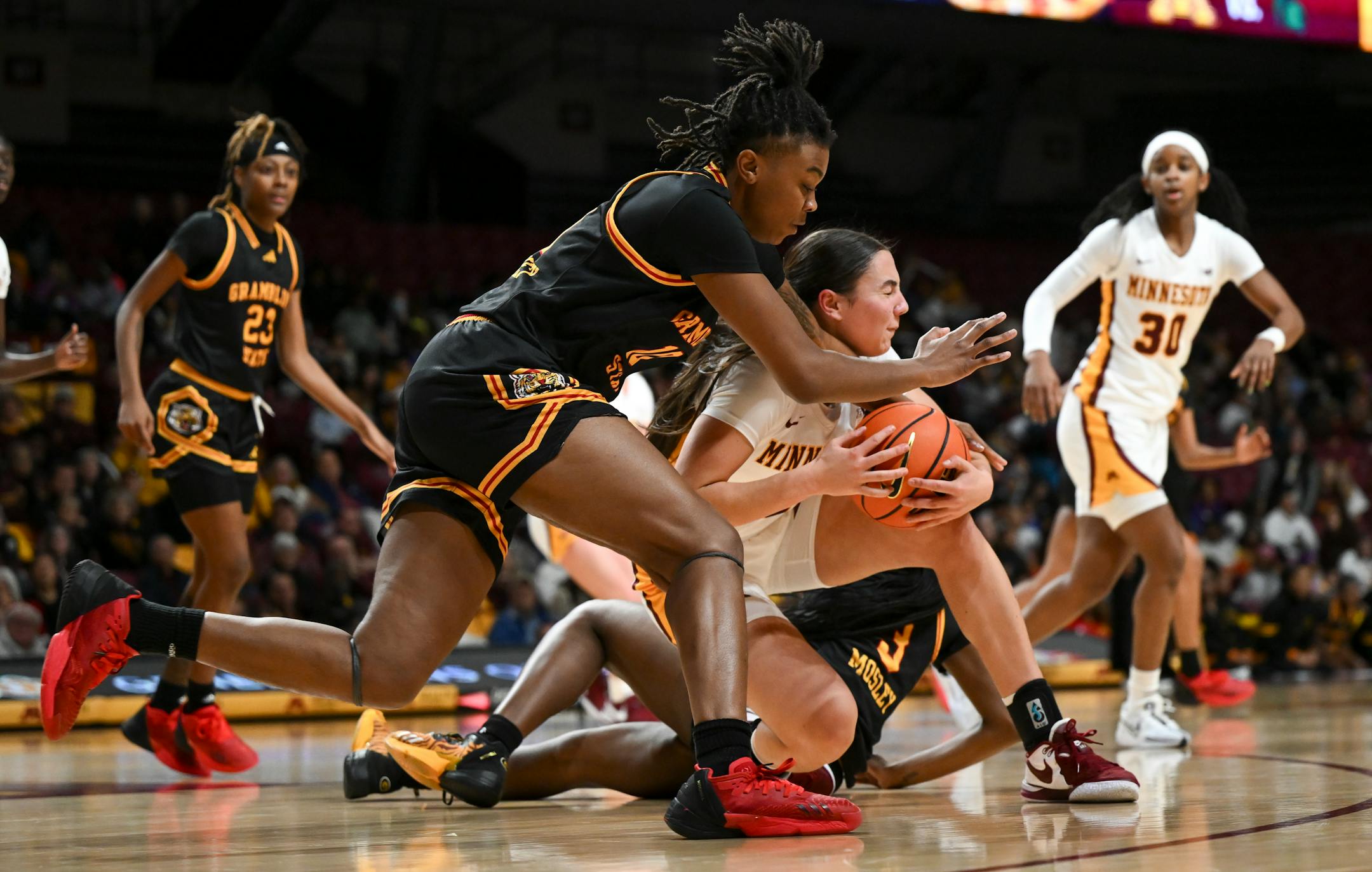 Grambling Lady Tigers guard Jordyn Carter (23), left, and guard Arianna Mosley (3) battle for the ball against Minnesota Gophers guard Maggie Czinano (5) in the second half.