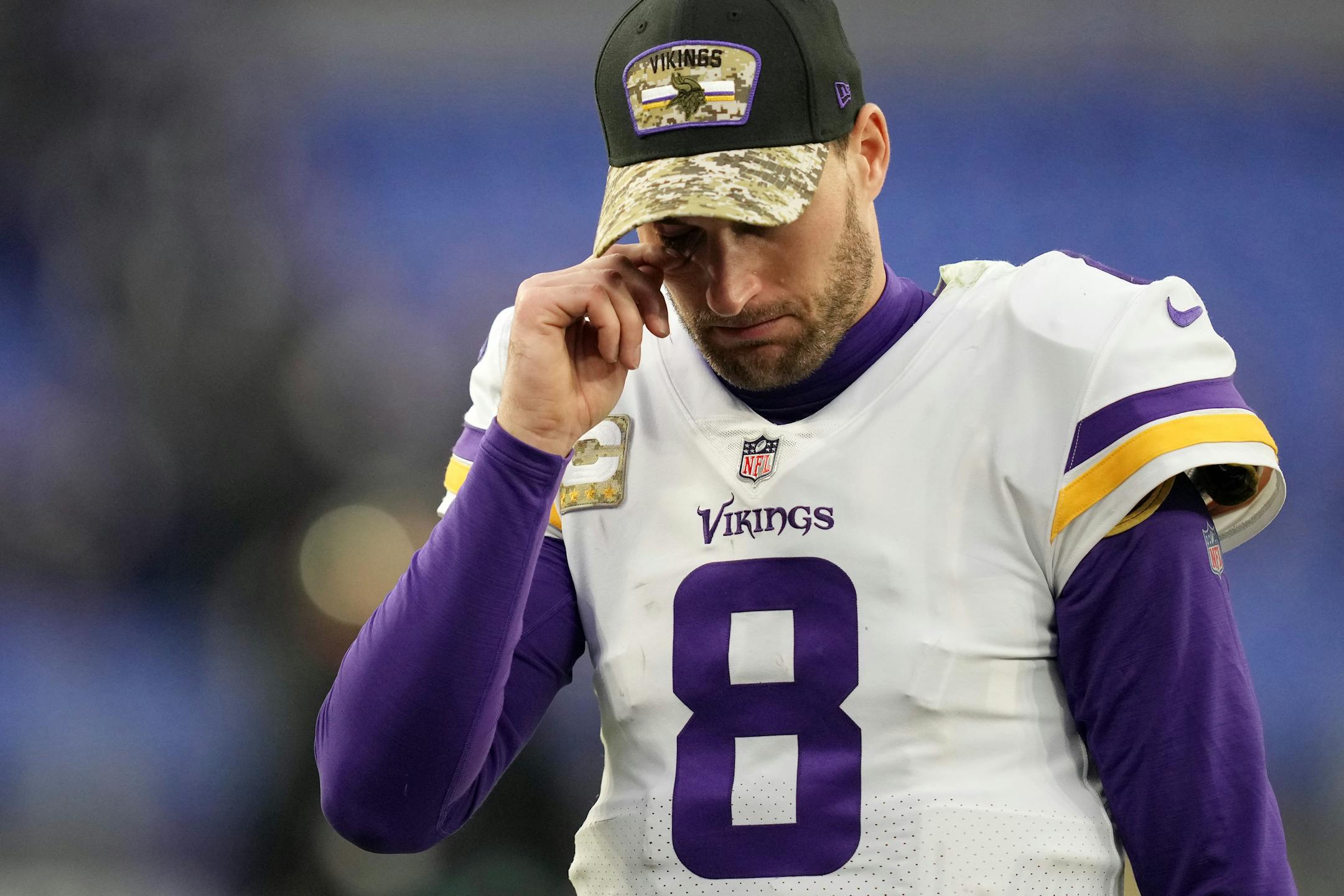 Vikings quarterback Kirk Cousins (8) wipes his eye as he walks off the field after losing an NFL game in overtime.