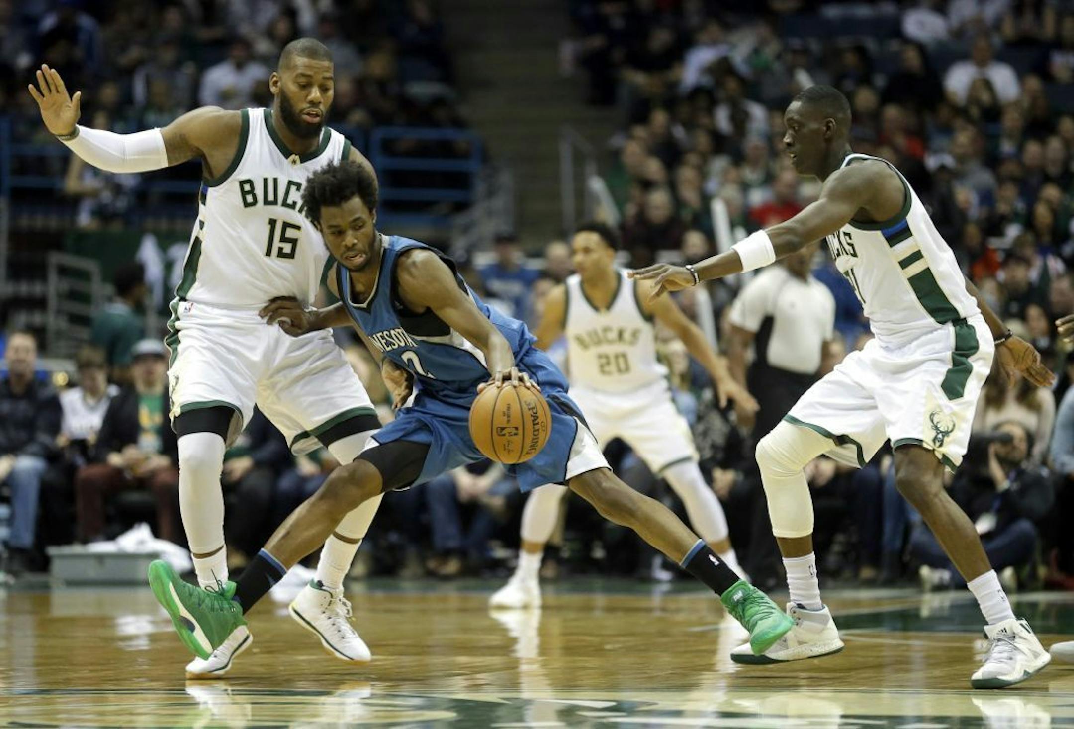 Minnesota Timberwolves' Andrew Wiggins, middle, dribbles between Milwaukee Bucks' Greg Monroe, left, and Milwaukee Bucks' Tony Snell, right, during the second half of an NBA basketball game Saturday, March 11, 2017, in Milwaukee.