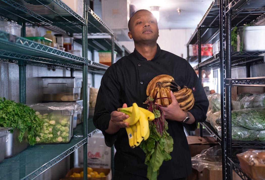Kamal Mohamed pulls produce out of a walk-in refrigerator at Parcelle in Minneapolis, his recently opened all-day cafe.
