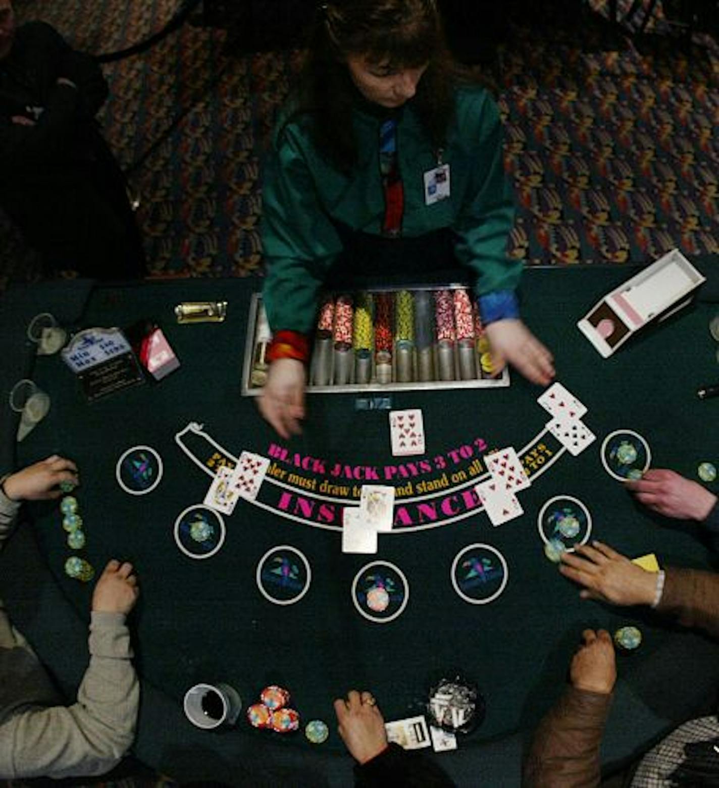 Jim Gehrz/Star Tribune 3/25/04 Julie Holt (top) deals blackjack to patrons at the Treasure Island Casino in Red Wing. The Casino and resort is run by the Prairie Lake Band.