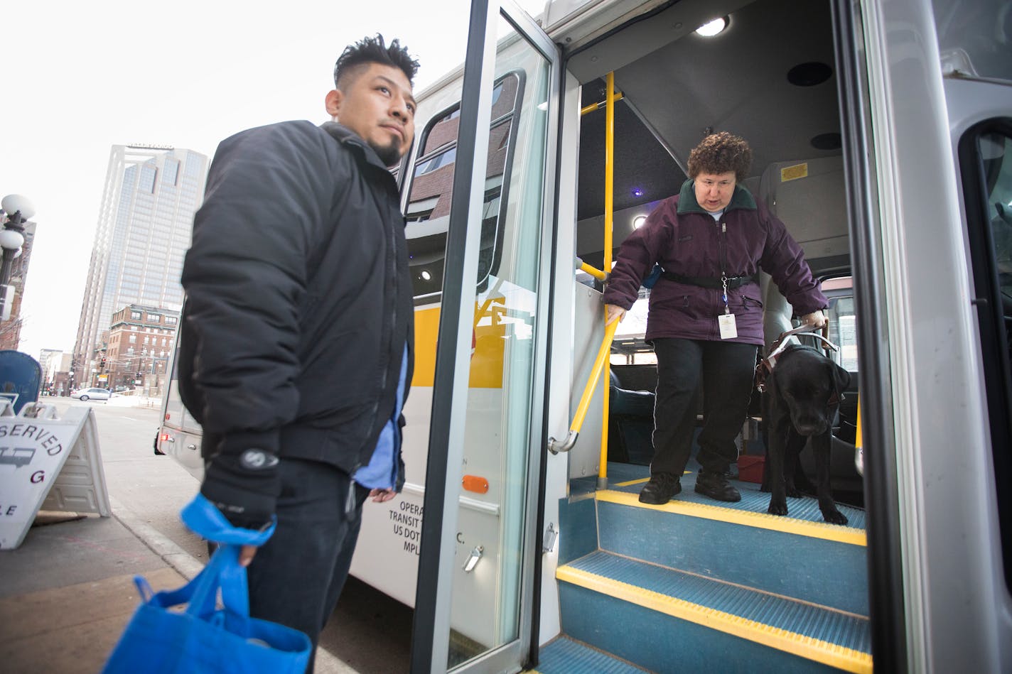 Lolly Lijewski, who uses a seeing eye dog named Jiffy for vision impairment, is helped off the Metro Mobility bus by driver Rigoberto Zuniga outside her work in St. Paul. ] LEILA NAVIDI � leila.navidi@startribune.com BACKGROUND INFORMATION: Lolly Lijewski, who uses a seeing eye dog named Jiffy for vision impairment, takes the Metro Mobility bus from her home in downtown Minneapolis to her workplace at the Minnesota Department of Human Services in downtown St. Paul on Tuesday, April 4, 2017. Grow