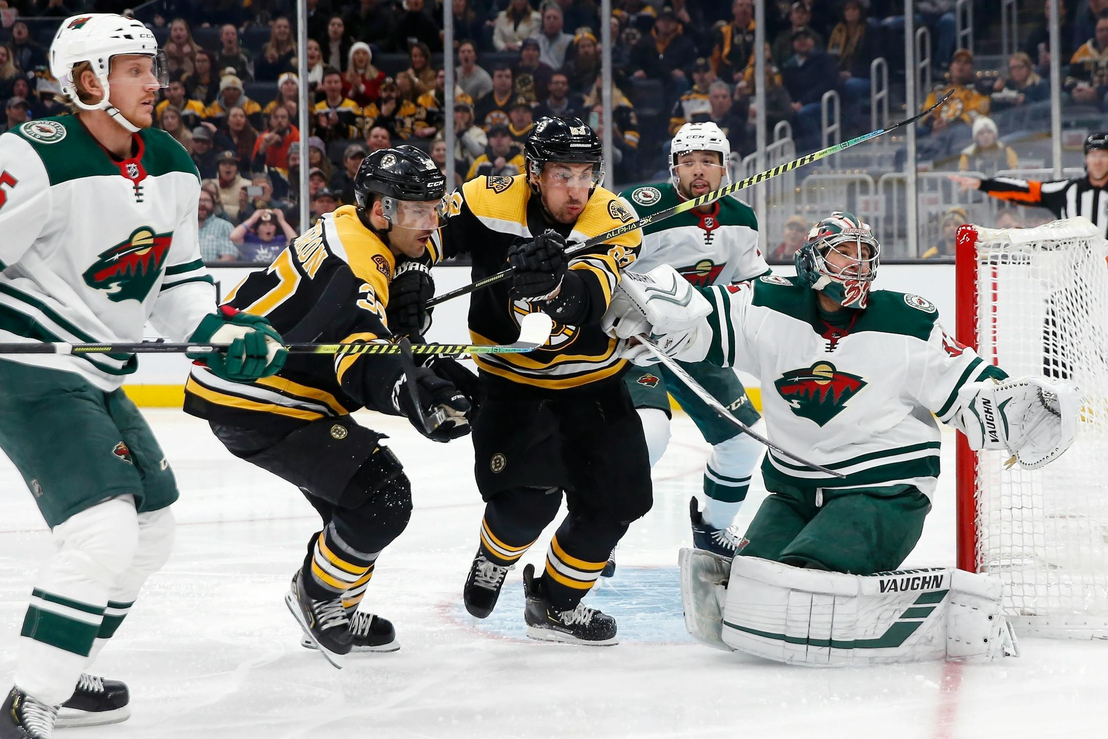 Boston's Patrice Bergeron (37) and Brad Marchand (63) chase a deflection off Wild goalie Alex Stalock