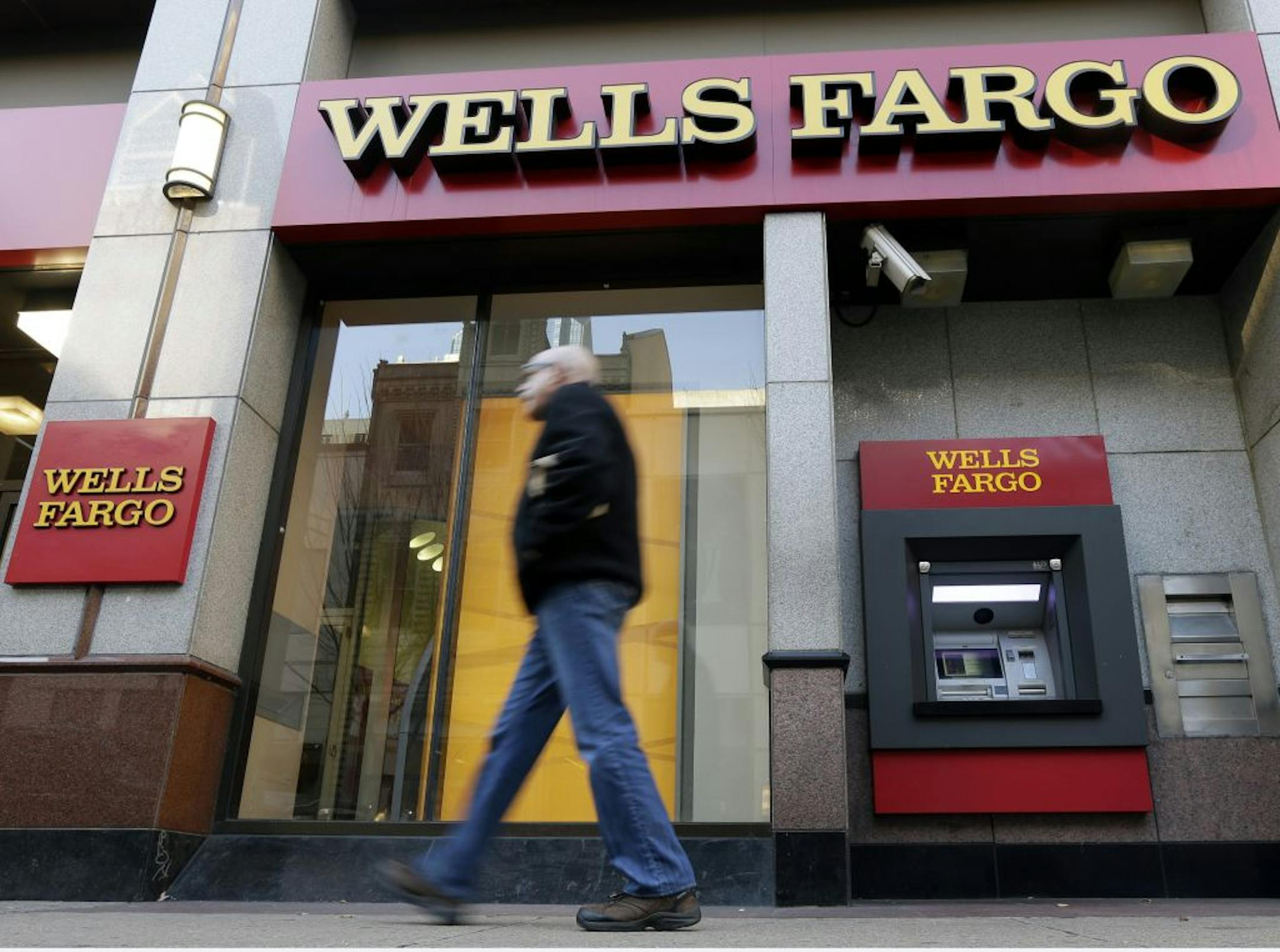 FILE - In this Wednesday, Dec. 19, 2012, file photo, a man walks past a Wells Fargo location in Philadelphia. Wells Fargo, the biggest U.S. mortgage lender, says it earned a record $4.9 billion in the fourth quarter, up 25 percent from the same period a year before. Revenue rose 7 percent, to $21.9 billion, beating the $21.3 billion expected by analysts polled by FactSet.
