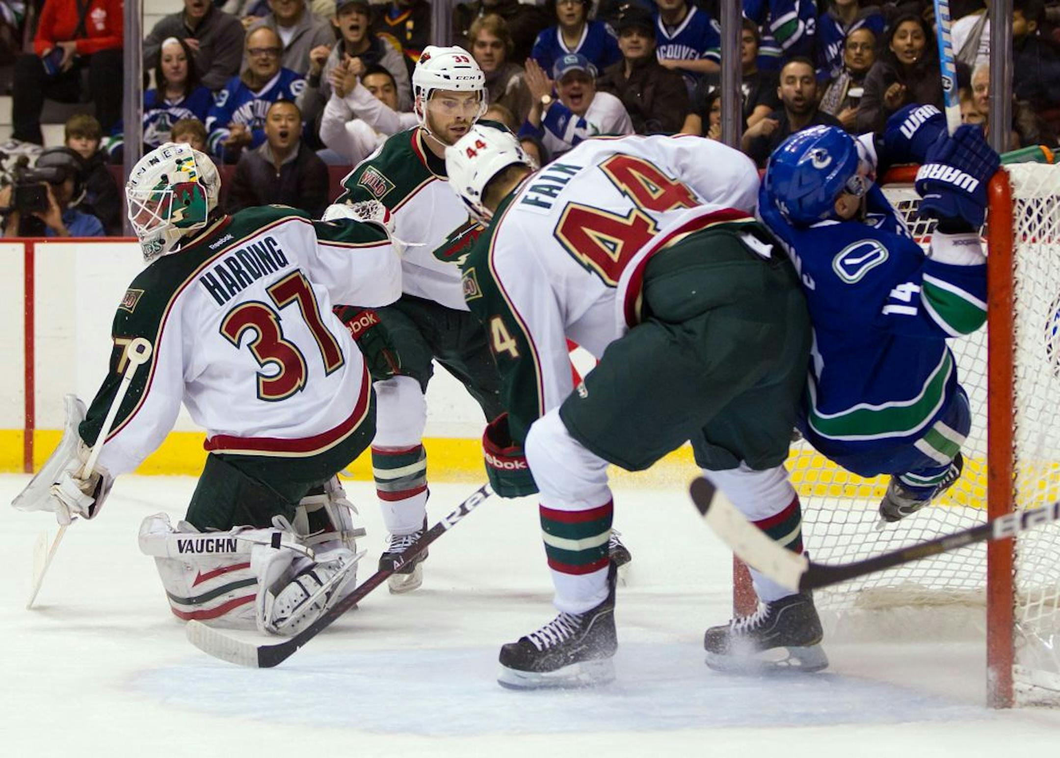 Vancouver's Alex Burrows, right, scored as he was checked into the net by the Wild's Justin Falk (44) on Wednesday night.