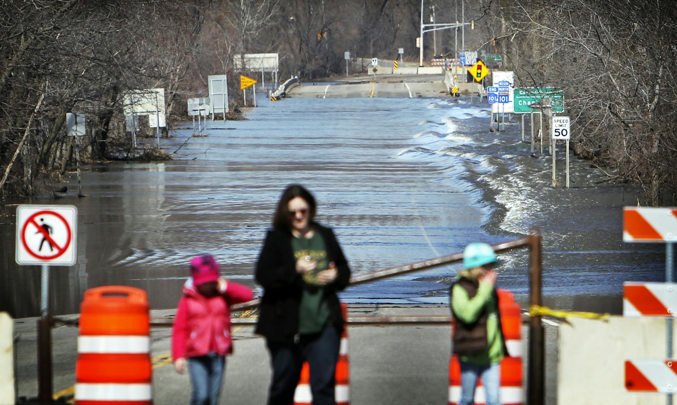 Despite flood waters receding, the swollen Minnesota River still flowed heavily over a closed portion of Highway 101 as pedestrians took in the sights.