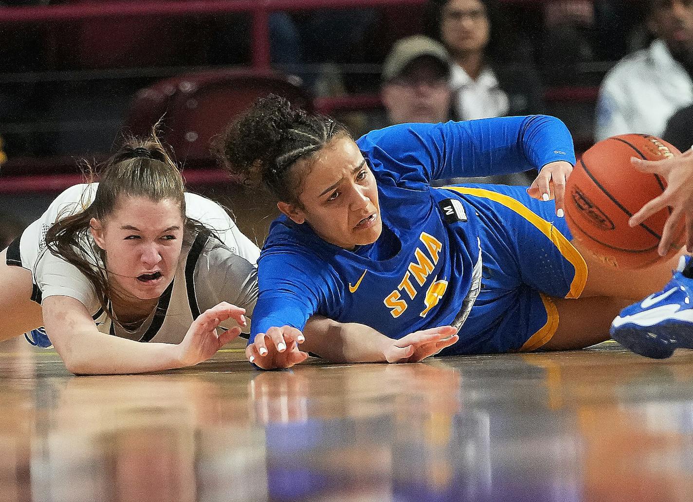 St. Michael-Albertville's Tessa Johnson (4) and Hopkins' Kelly Boyle (2) battle for a loose ball Saturday, March 18, 2023 during the first half of the Class 4A girls' basketball state championship at Williams Arena in Minneapolis, Minn. ]