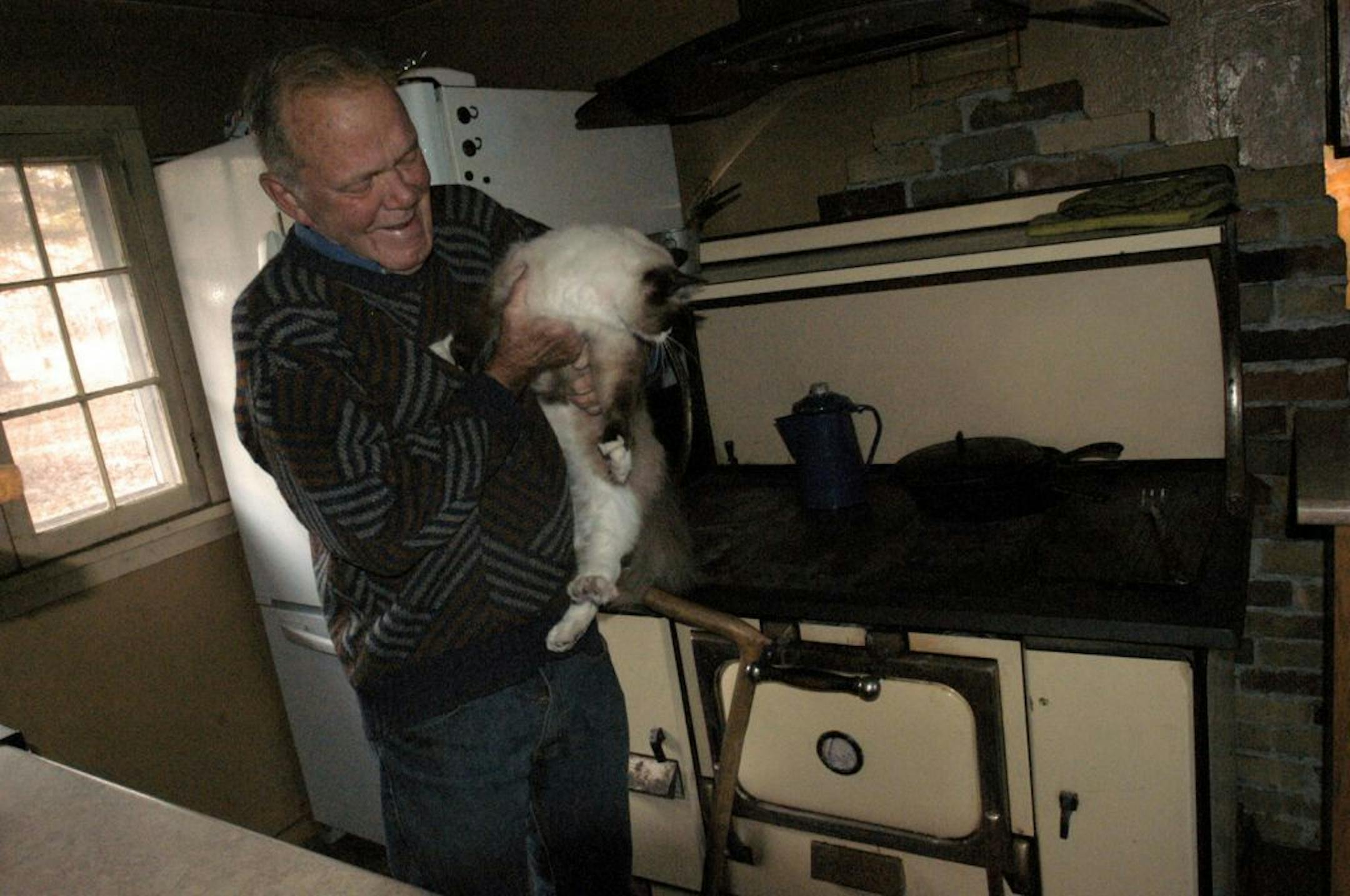 Win Borden held Marcus the cat as he talked about his wood stove, made famous in his Facebook postings. The stove has been in its place since 1931. File photo from November 2012.