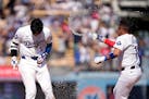 Dodgers star Shohei Ohtani, left, is sprayed with water by Miguel Rojas after Ohtani hit a walk-off single during the 10th inning to beat the Reds on 
