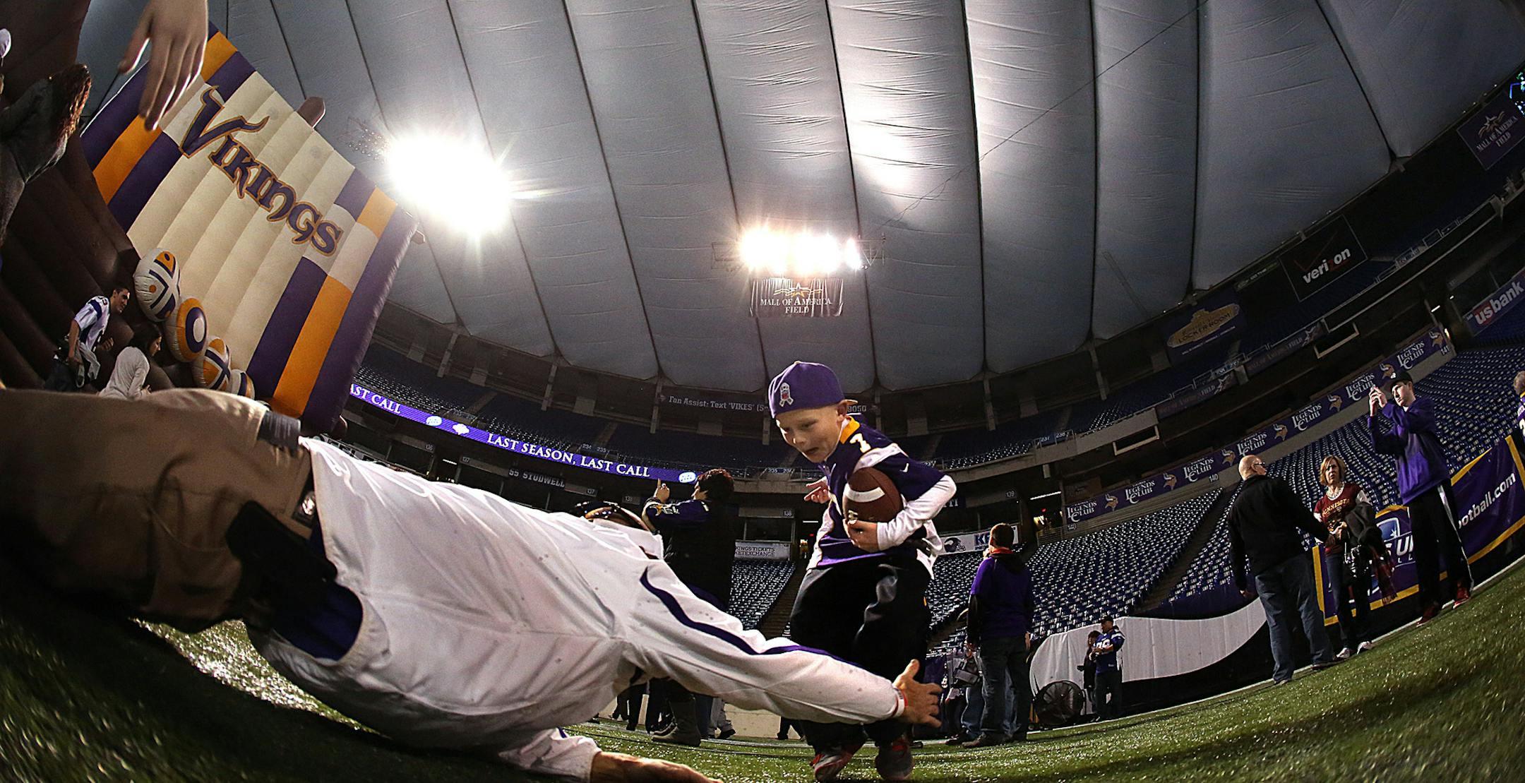 Eight-year-old Jaxen Peterson, Ventura, IA, played football with his father, Brian (tackling Jaxen) and his older brother, Ty, 10 (not pictured). Brian said that season tickets to the Vikings have been in his family since 1980, when his father first bought seats. ] JIM GEHRZ ‚Ä¢ jgehrz@startribune.com / Minneapolis, MN / December 28, 2013 / 4:30 PM BACKGROUND INFORMATION: About 6,000 Vikings fans signed up for one last chance to take photos on the field, to look over the Vikings