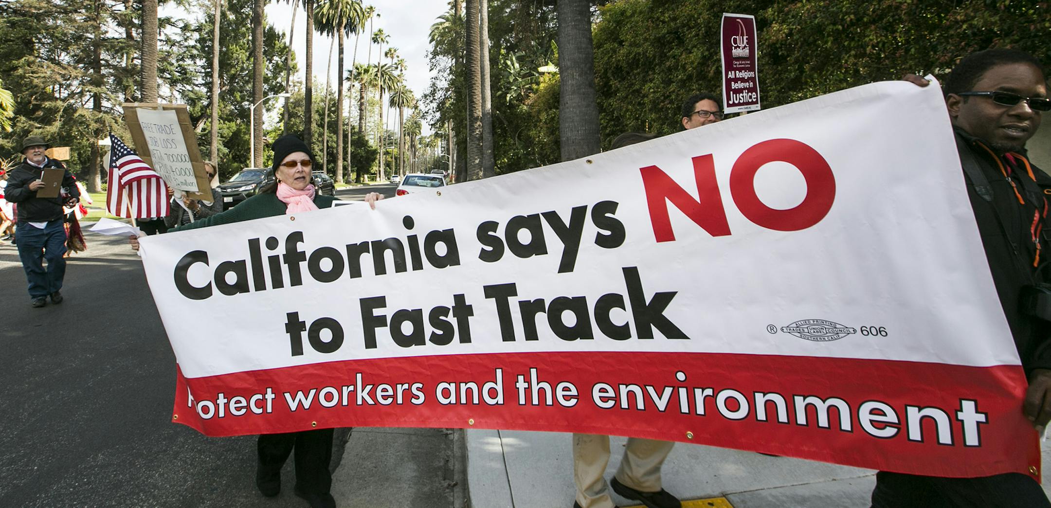 Los Angeles community members take to the streets of Beverly Hills to demand that Hillary Rodham Clinton oppose the Trans-Pacific Partnership (TPP) and Trade Promotion Authority (TPA) known as &#xec;The Fast Track,&#xee; in Beverly Hills, Calif., Thursday, May 7, 2015. Clinton is spending Thursday at three private fundraisers around LA, with tickets costing $2,700 per person. The front-runner for the Democratic nomination is on a three-day swing through California. (AP Photo/Damian Dovarganes) O