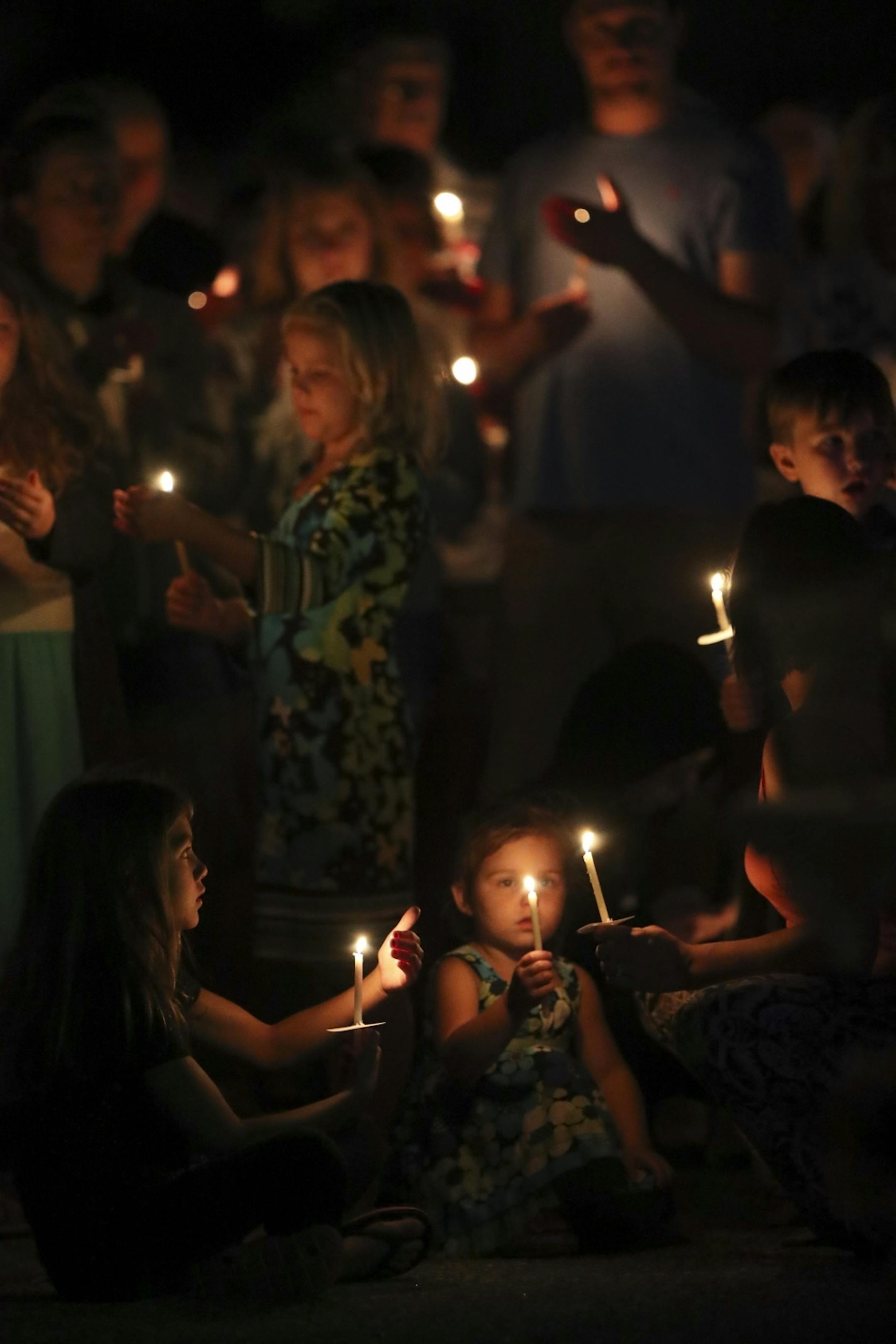 Mourners with their lit candles during the prayer vigil for their Alayna Ertl Tuesday night in the parking lot of St. Anthony Church in Watkins.