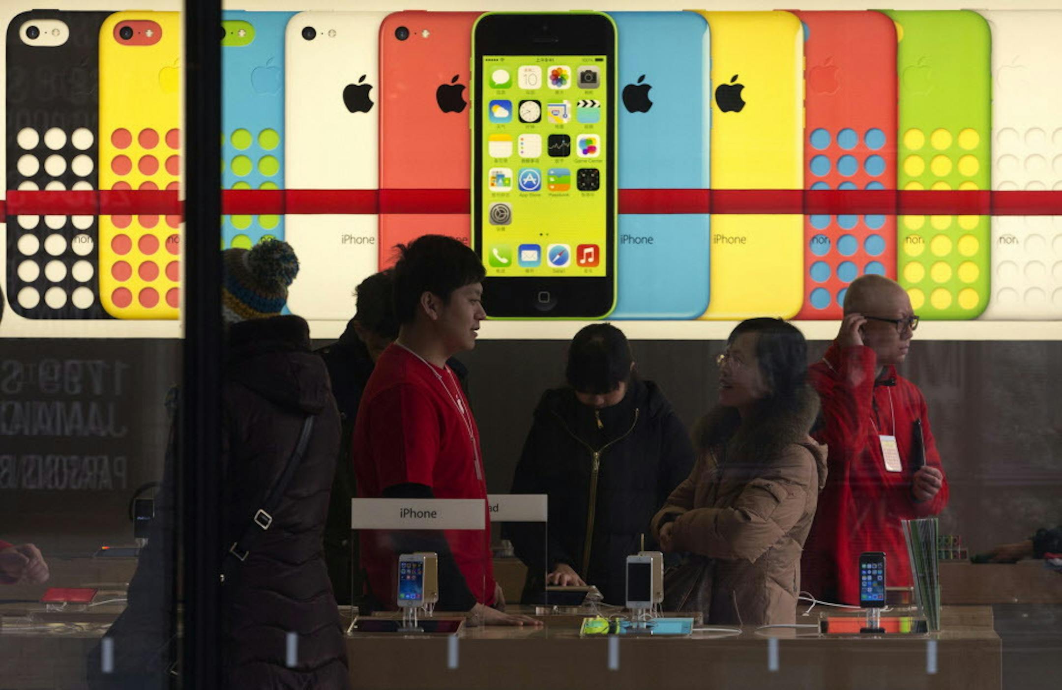 A woman talks to a salesperson in front of an advertisement for iPhones at Apple's retail store in Beijing Monday, Dec. 16, 2013. Apple Inc. might have a chance to pep up cooling iPhone sales in China if it finally can reach a deal with the worldís biggest phone carrier. (AP Photo/Ng Han Guan)