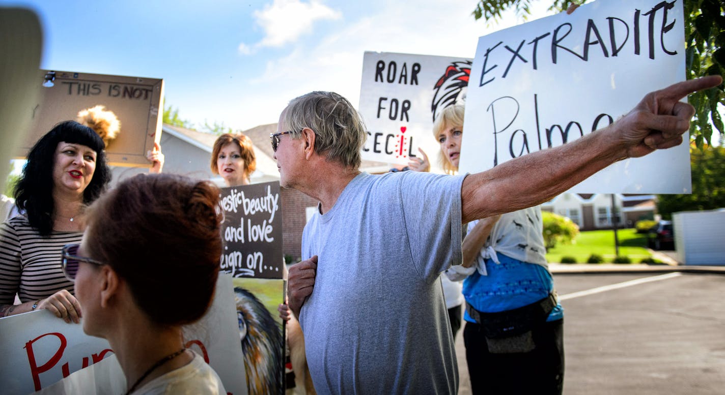 Demonstrators heckled one of Walter Palmer's patients, Thomas Dressel, right, who paused to speak to the media, outside Palmer's dental practice, Tuesday, Sept. 8, 2015, in Bloomington, Minn. One said "I bet he has a confederate flag in his car window." He pointed out that he did not. Palmer, after weeks out of the public eye, was the subject of an international uproar after he was identified as the hunter who killed the famous lion Cecil, in Zimbabwe. (Glen Stubbe/Star Tribune via AP) MANDATORY