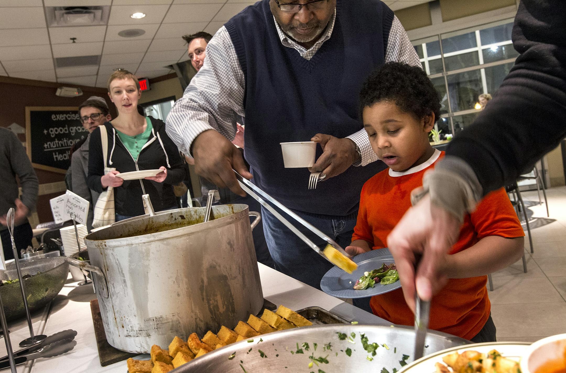 Urban Ventures Ready Set Work director Stan Hill loaded a plate for grandson Ishaan Crawford, 5, at the feast in south Minneapolis. See more photos at www.startribune.com/lifestyle.