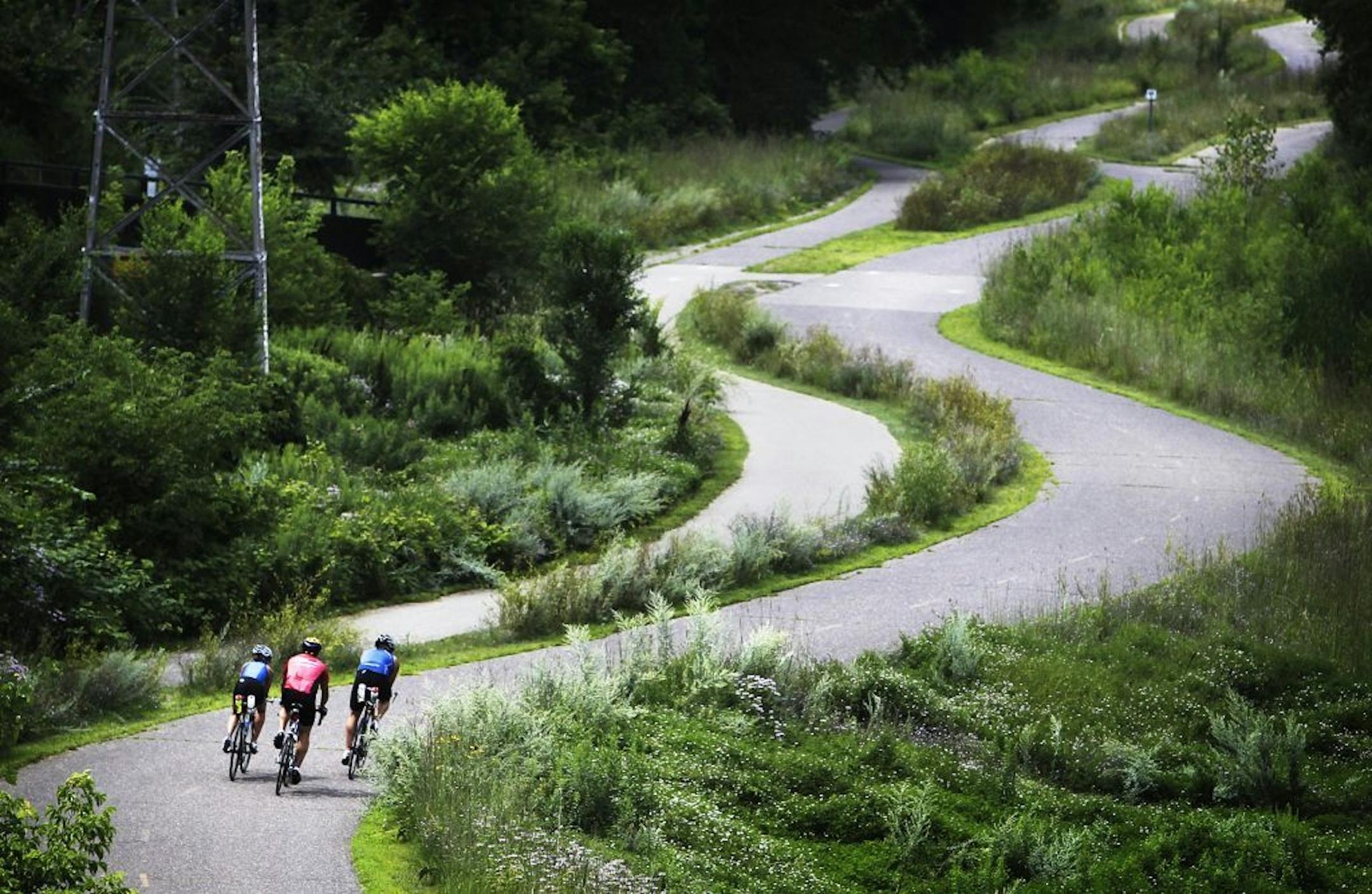A trio of bicyclists, seen from a bridge of Cedar Lake Parkway, take the winding Greenway bike trail near Cedar Lake in Minneapolis Friday, July 29, 2011.