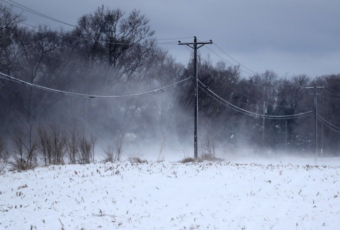 Howling winds blow a fresh coating of snow through a field and over 70th St. S. Saturday, March 31, 2018, in Cottage Grove, MN.