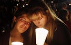 Kristen Sterner, left, and Carrissa Welding, both students at Umpqua Community College, embrace each other during a candlelight vigil for those killed
