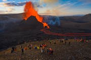 People watch as lava flows from an eruption from the Fagradalsfjall volcano on the Reykjanes Peninsula in southwestern Iceland on Tuesday, May 11, 202
