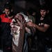 Palestinians rescue a woman survived after the Israeli bombardment on a residential building of Abu Alenan family in Rafah, southern Gaza Strip, early
