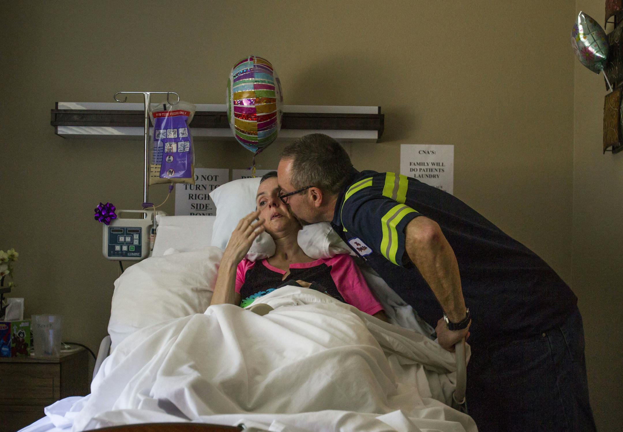 Tim Fink gives his wife, Molly, a kiss as she rests in her bed at Avamere Riverpark of Eugene in Eugene, Ore., July 17, 2017. The couple have used GoFundMe as a resource to help raise money for the medical expenses associated with Molly Fink's brain injuries. (Rhianna Gelhart/The Register-Guard via AP)