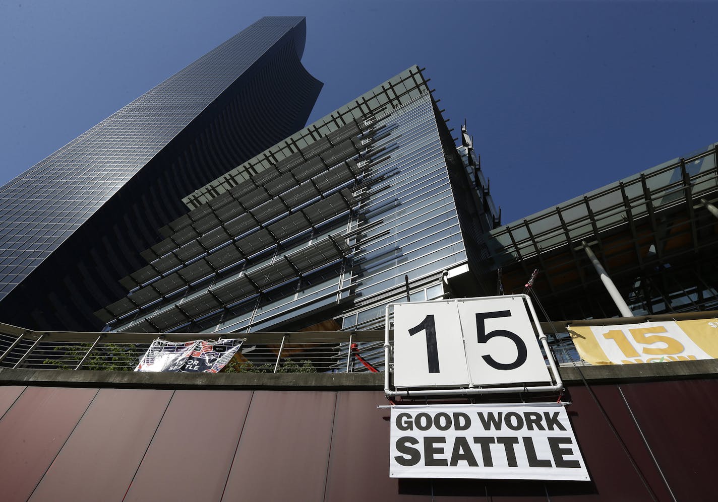 FILE - In this June 2, 2014, file photo, a sign that reads "15 Good Work Seattle" is displayed below Seattle City Hall, right, and the Columbia Center building, left, after the Seattle City Council passed a $15 minimum wage measure. As states and cities gradually implement new laws to raise wages to at least $15 an hour, they are confronting a challenge experts say has long bedeviled the nation&#xed;s municipalities: policing tens of thousands of businesses to obey wage laws. (AP Photo/Ted S. Wa