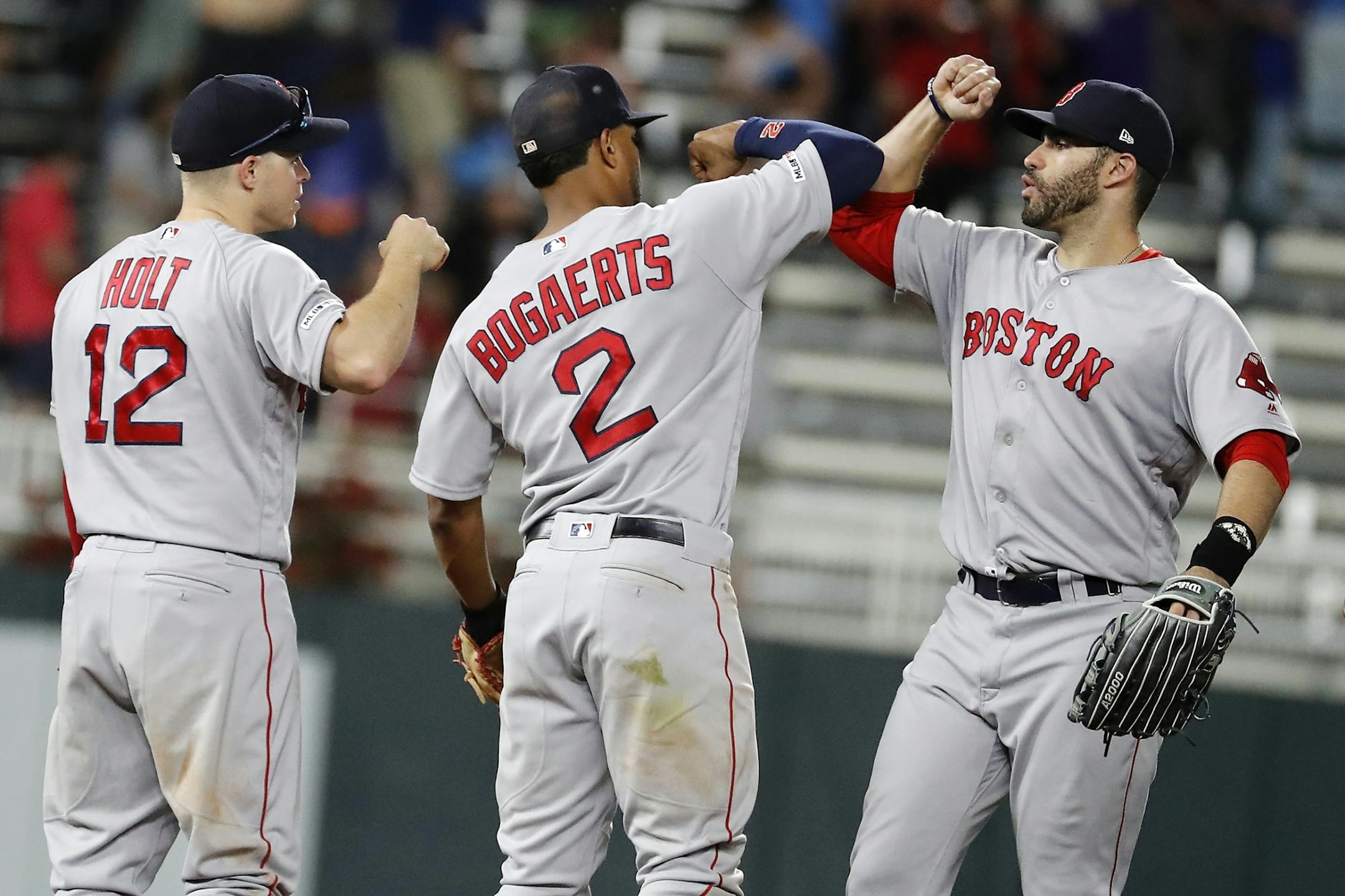 Boston Red Sox second baseman Brock Holt (12), from left, Boston Red Sox shortstop Xander Bogaerts (2) and Boston Red Sox left fielder J.D. Martinez (28) celebrate their win over the Minnesota Twins.