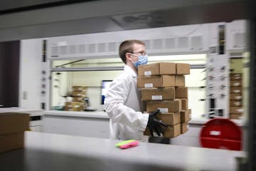 University of Minnesota Genomics Center researcher Brandon Vanderbush carried a dozen boxes containing COVID-19 tests back to his workstation for proc