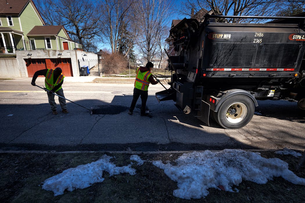 City of St. Paul workers patch potholes along 6th Street on Friday.
