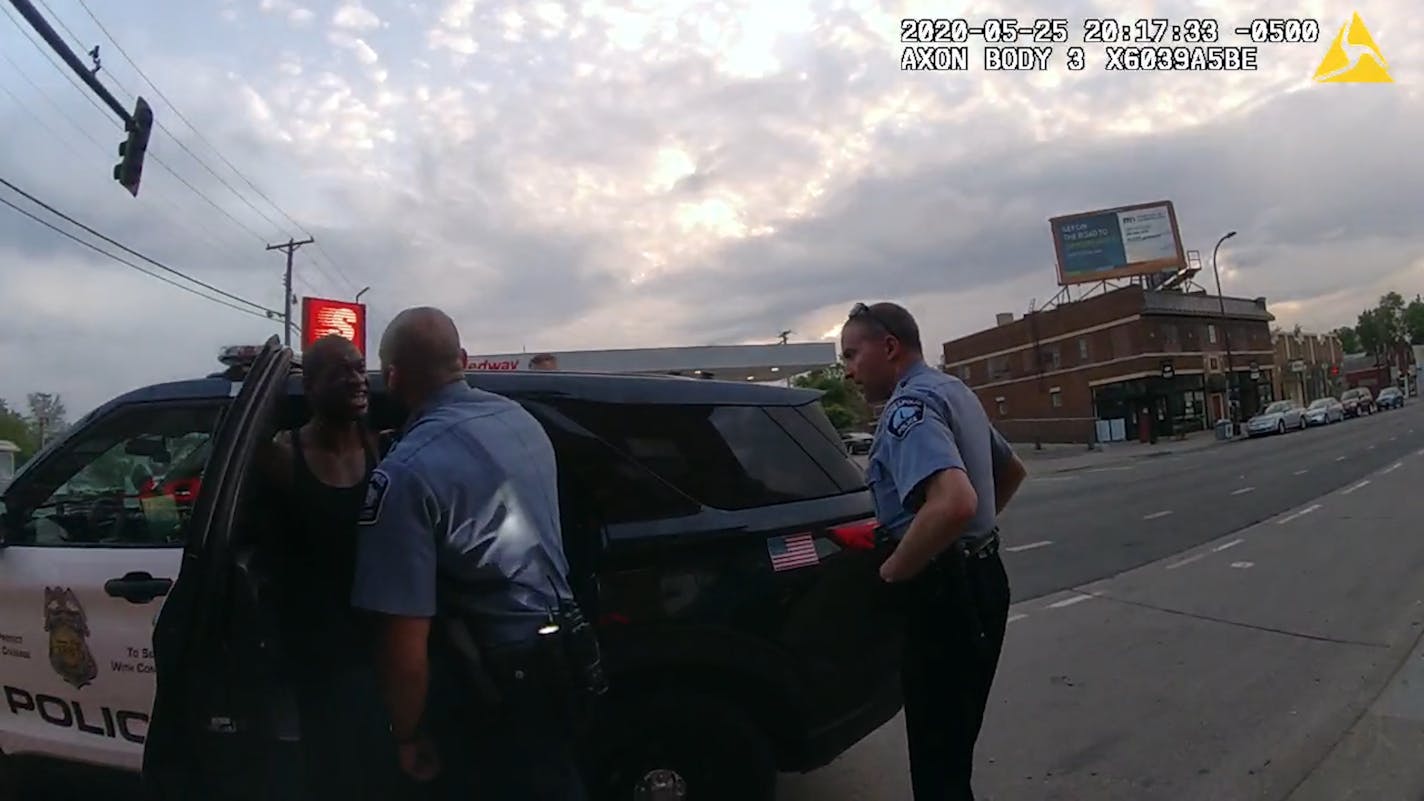 A screenshot from ex-officer Tou Thao's body camera shows J Alexander Kueng and Derek Chauvin attempting to put George Floyd into the back of a squad.