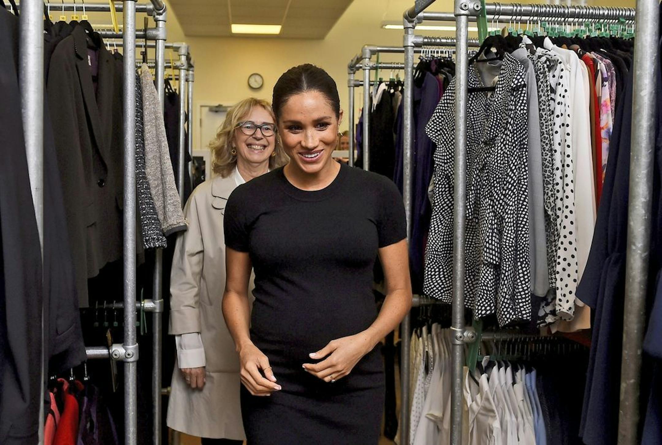 Meghan, the Duchess of Sussex, accompanied by Juliet Hughes-Hallett, as they walk past racks of clothes at the Smart Works charity career centre in West London, Thursday Jan. 10, 2019. Meghan on Thursday has become patron of the Smart Works charity that supports unemployed women to return to work.