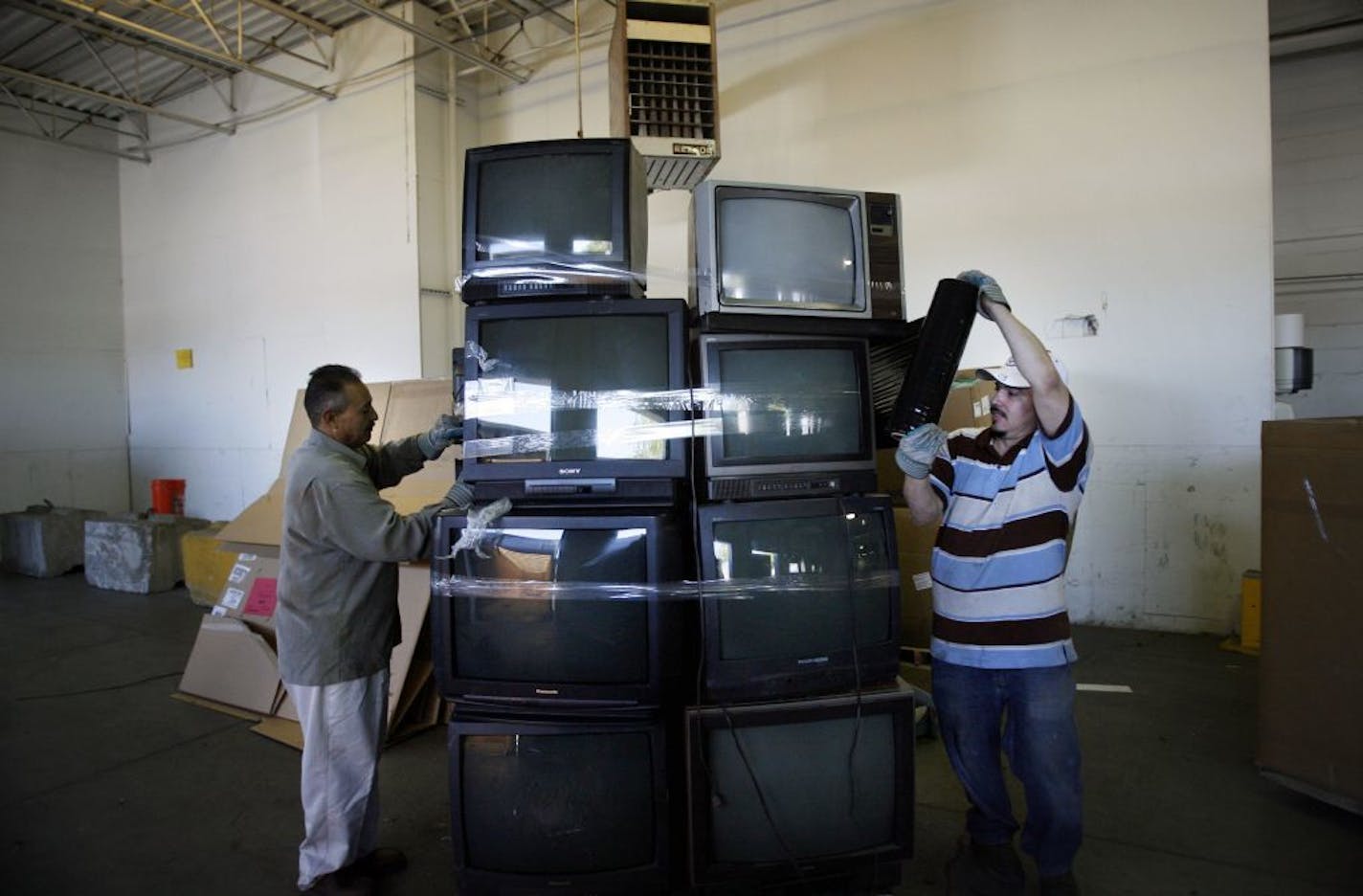 RENEE JONES SCHNEIDER � reneejones@startribune.com Minneapolis, MN - MAy 2, 2007 - Daniel Hernandez and Juan Carlos shrink-wrapped a stack of televisions delivered to be recycled at Asset Recovery Corp. in St. Paul Wednesday afternoon.