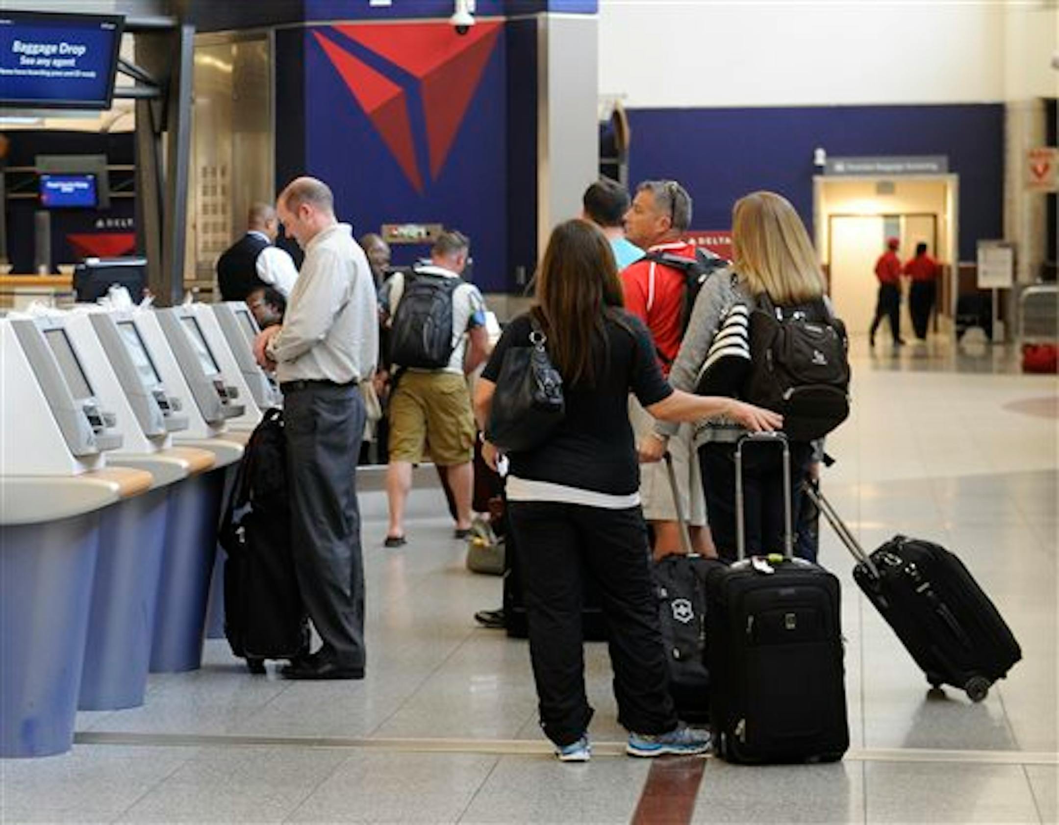 In this Friday, Sept. 27, 2013 photo, Delta Air Lines passengers line up to check luggage at Hartsfield-Jackson Atlanta International Airport, in Atlanta. Delta customers now have the option to purchase an upgrade that includes a free checked bag, among other perks. (AP Photo/John Amis)