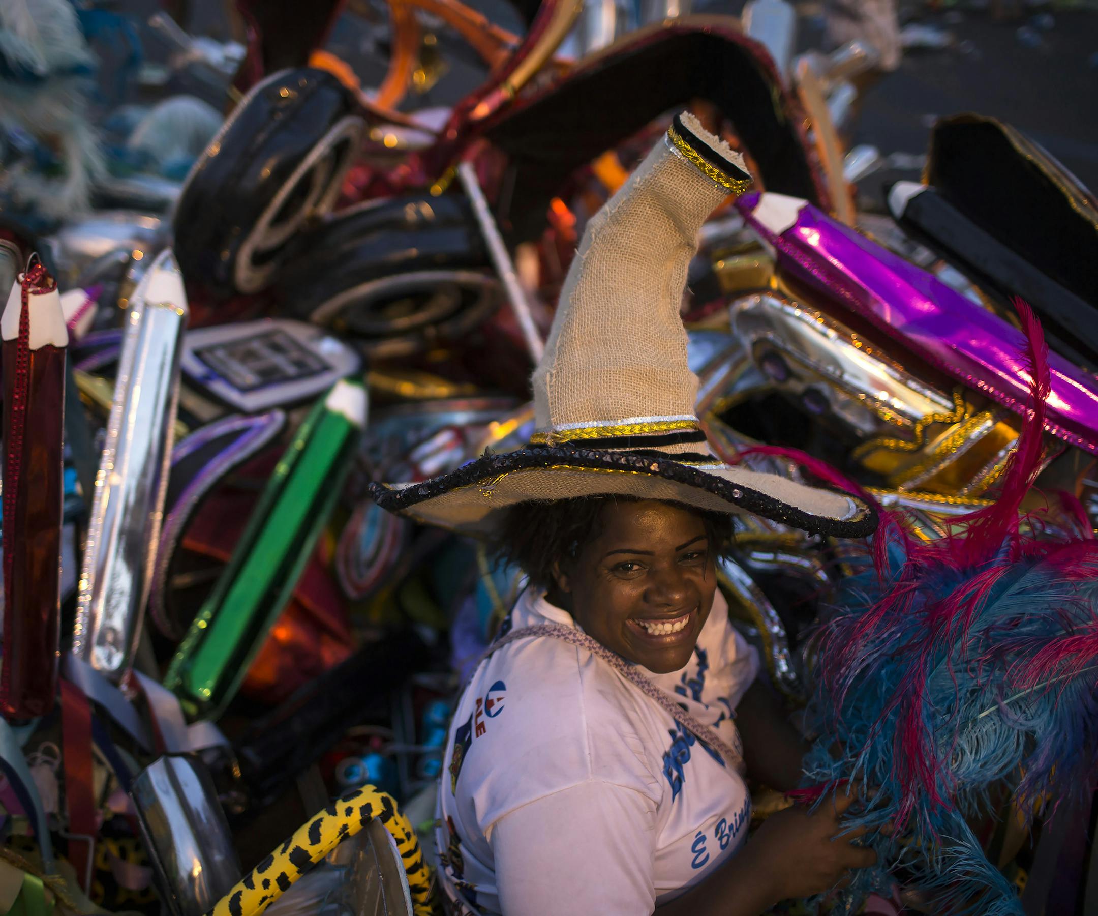 Elaine da Silva Moraes poses for a photo backdropped by piles of discarded costumes after carnival celebrations at the Sambadrome in Rio de Janeiro, Brazil, Tuesday, March 4, 2014. Moraes is a "catadora," or trash picker, and hundreds of others like her, for whom Carnival represents an annual boon. Dressed in a patchwork of costume parts rescued from the detritus, Moraes fills plastic garbage bags with her treasures - feathers, props, headgear and costly fabrics that she re-sells or transforms i