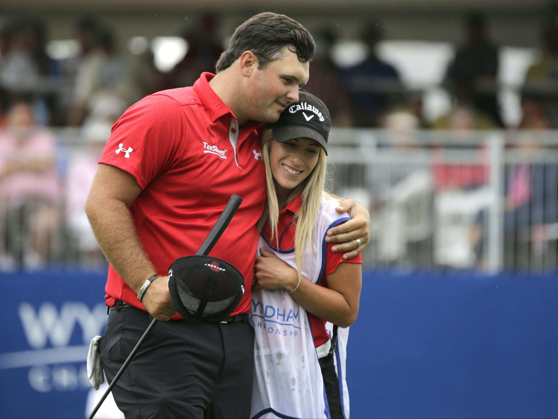 Patrick Reed, left, embraces his wife and caddie, Justine Reed, right, after making a birdie putt on the ninth hole during the second round of the Wyndham Championship golf tournament at Sedgefield Country Club in Greensboro, N.C., Friday, Aug. 16, 2013. (AP Photo/Chuck Burton)