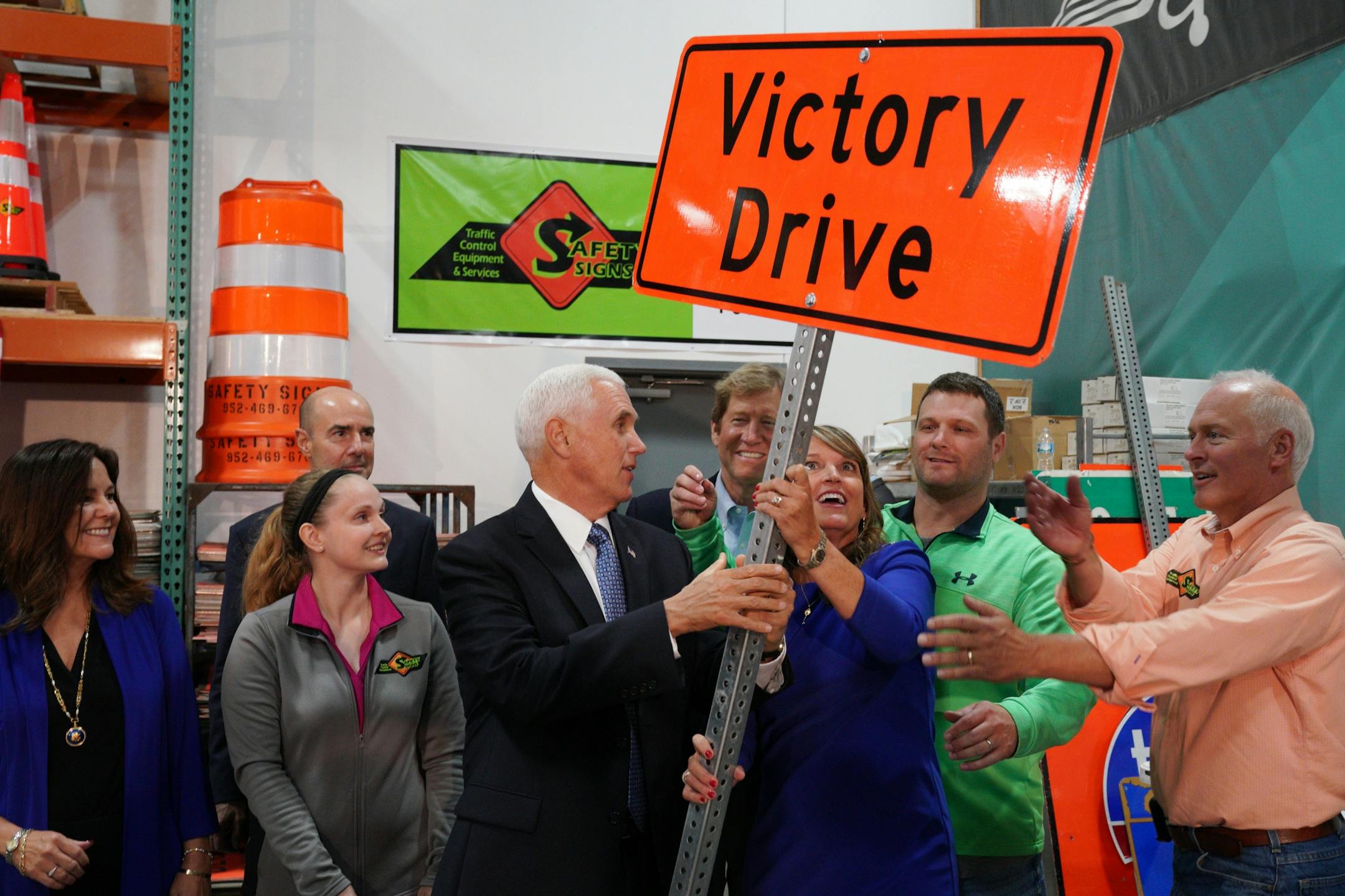Safety Signs vice president Jay Blanchard, right, his wife, company president Sue Blanchard, and U.S. Vice President Mike Pence, laughed as they tried to hold up a sign for a photo following a tour of their sign making shop.
