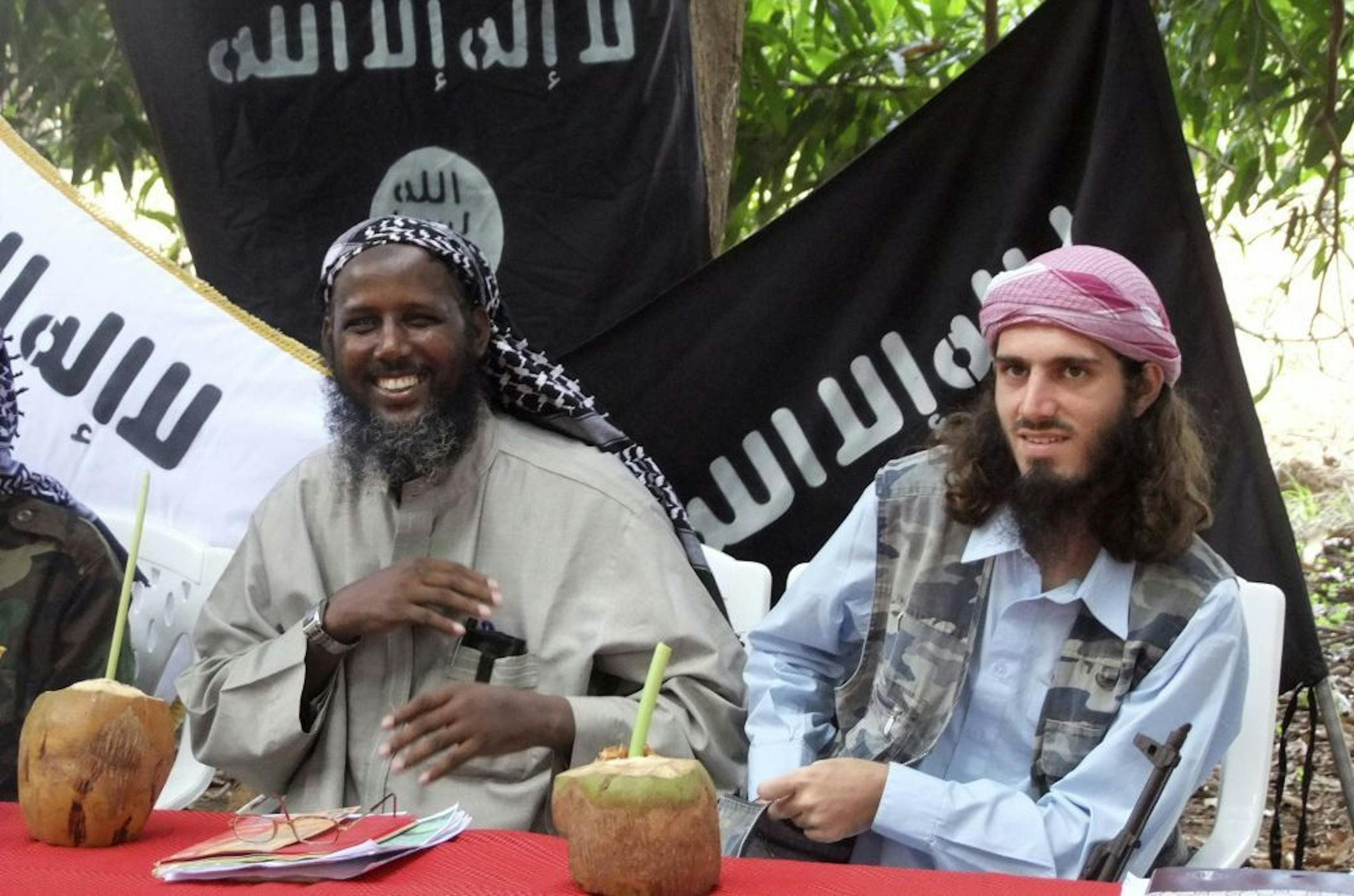 FILE - In this Wednesday, May 11, 2011 file photo, American-born Omar Hammami, also known as Abu Mansur al-Amriki, right, and deputy leader of al-Shabab Sheik Mukhtar Abu Mansur Robow, left, sit under a banner which reads "Allah is Great" during a news conference by the militant group at a farm in southern Mogadishu's Afgoye district in Somalia. Hammami - whom the FBI named as one of its most wanted terrorists in November - has engaged in a public fight with al-Shabab over nearly the last year a