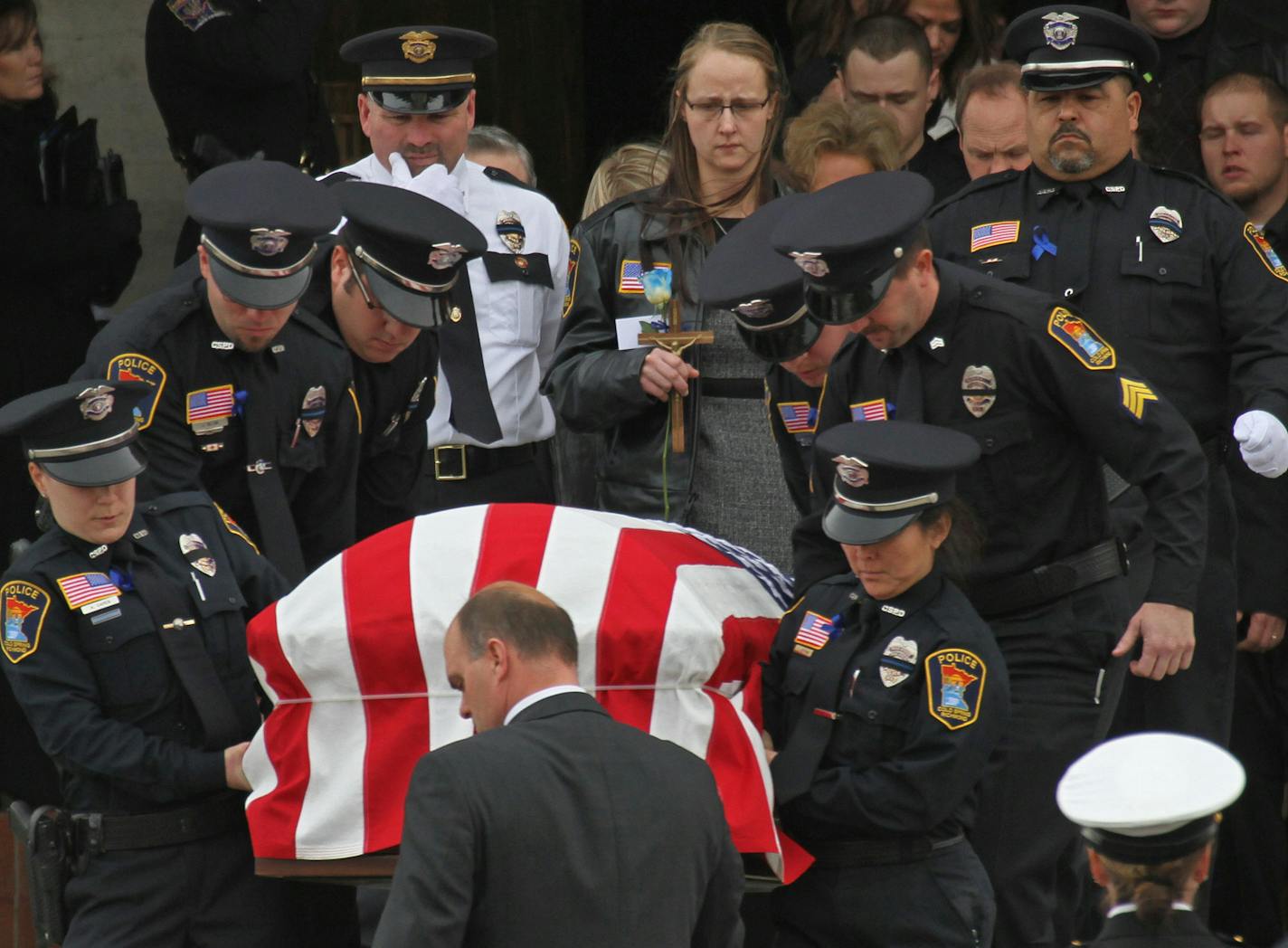 The casket of Cold Spring MN. police officer Tom Decker was carried from St. John's Abby and University church after services finished on 12/5/12.] Bruce Bisping/Star Tribune bbisping@startribune.com Tom Decker/program (WOMAN IN CENTER BACK WITH LEATHER JACKET AND HOLDING CROSS is THE WIDOW OF DECKER- CHECKING NAME) ORG XMIT: MIN1212051427000753