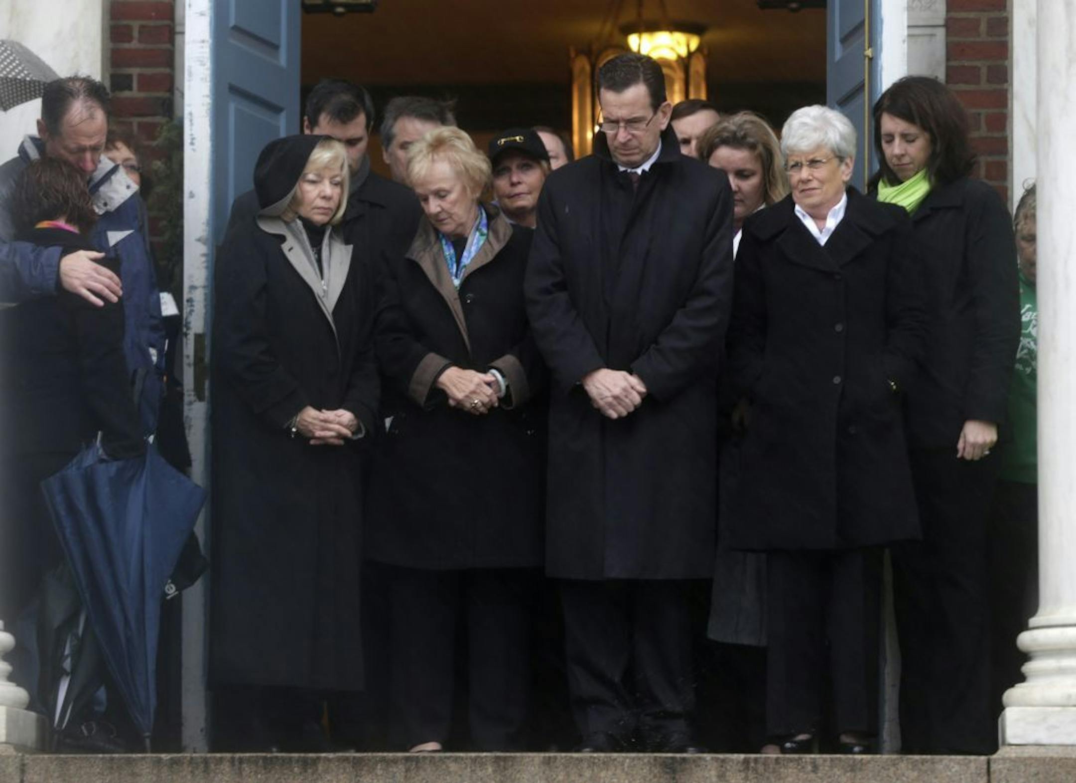 Connecticut Gov. Dan Malloy, center, stands with other officials to observe a moment of silence while bells ring 26 times in Newtown, Conn., Friday, Dec. 21, 2012, in honor of the victims who were killed last Friday during the shooting at Sandy Hook Elementary School.
