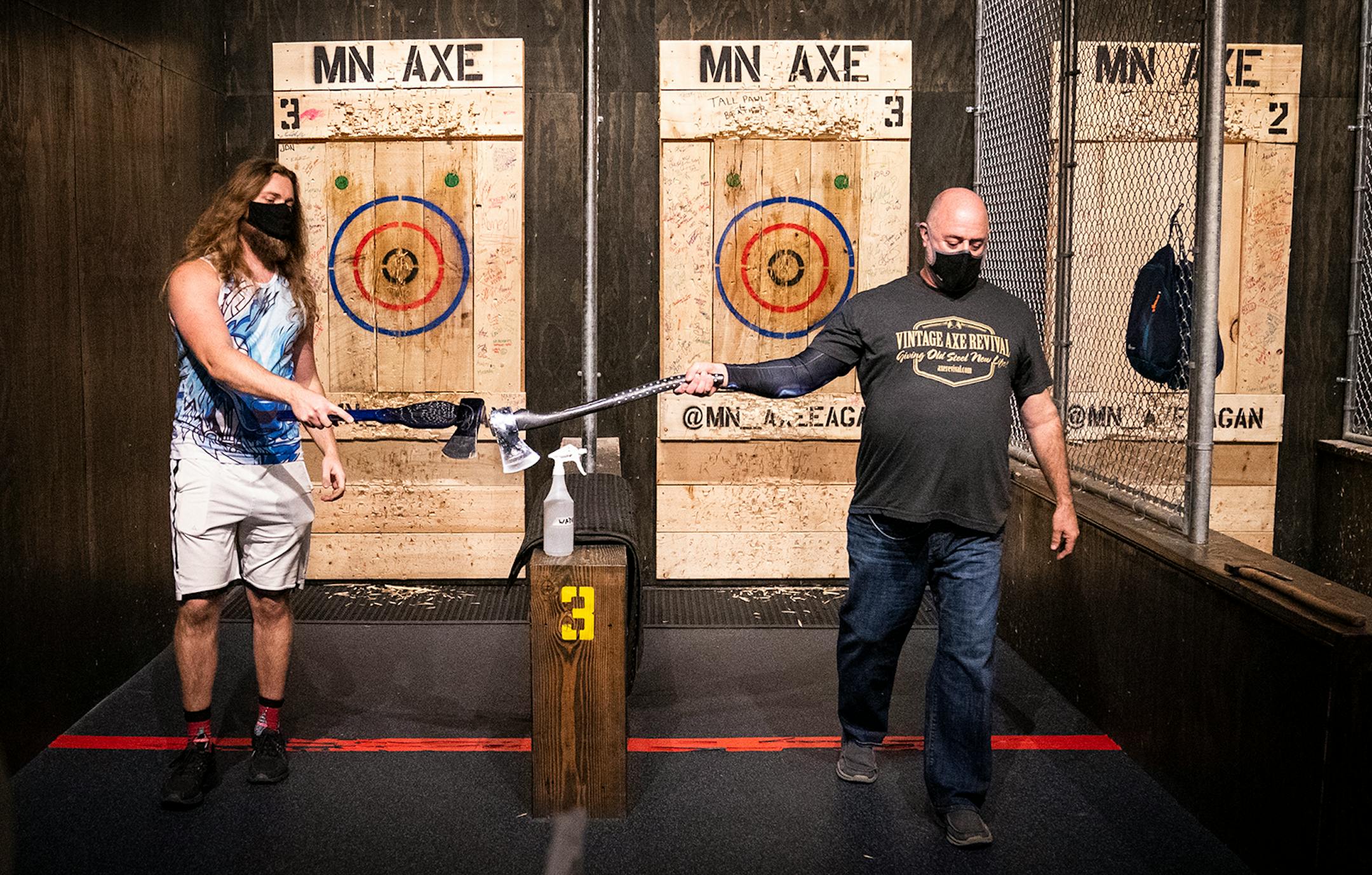 Austin Luecke, left, and David Lewis tap axes, which is like a high five, while practicing for the World Axe Throwing Championship at MN Axe in Eagan.